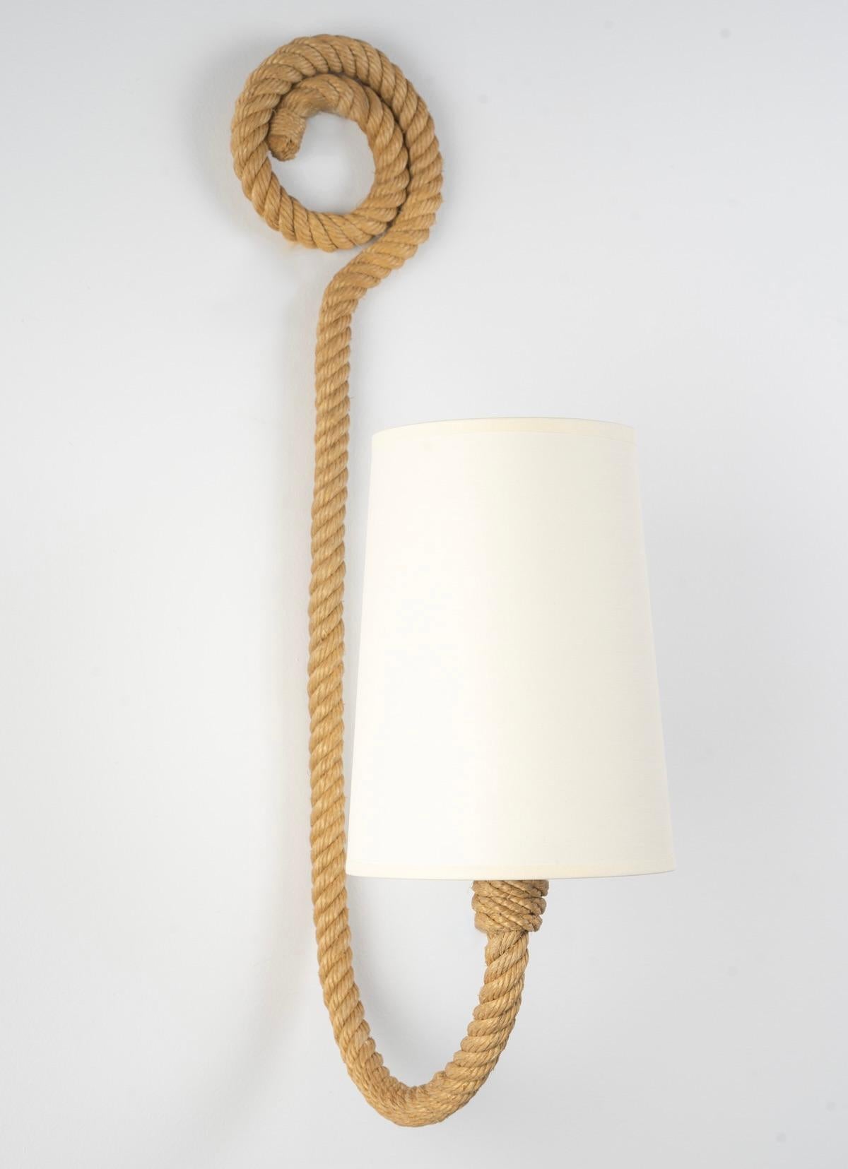 Composed of a rope arm that curves forward on the lower part and is covered by a conical shade in off-white cotton reworked to match.
On the upper part, the rope arm ends in a spiral that beautifully decorates the sconce.
1 light arm.

Adrien Audoux
