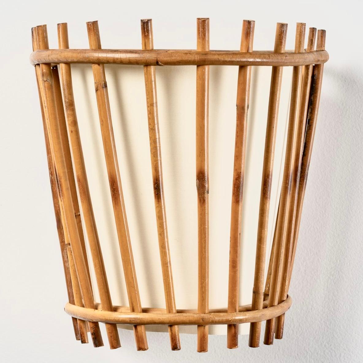 Composed of thin rattan rods placed vertically and assembled by two curved rattan rods placed horizontally on the top and bottom of the sconce.
An off-white cotton lampshade is placed inside the sconce following the curved cord.
1 bulb.
