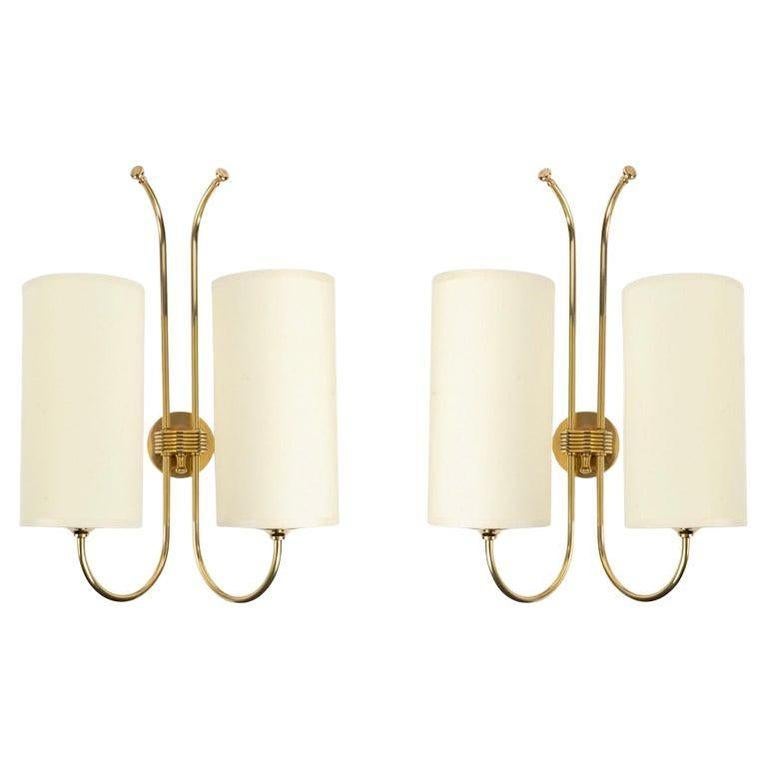 Composed of a wall base of cylindrical shape in gilded brass, on the front face is positioned a half-cylinder receiving two rods in gilded brass placed vertically, distributed on each side of the wall lamp.
On the lower part, the rods are curved,