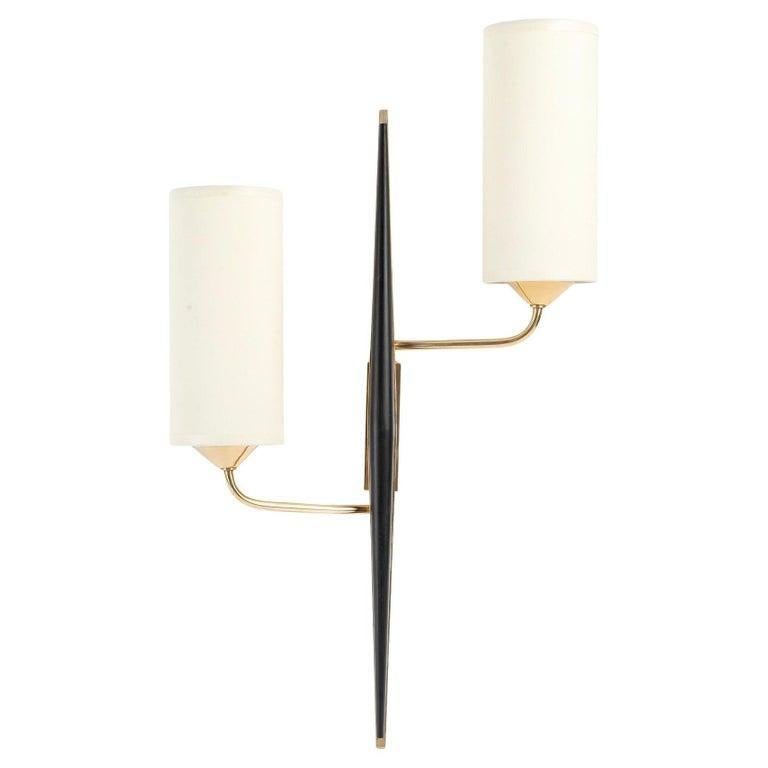 Composed of a central stem in the shape of a spindle in gilded brass, decorated in front of a spindle in blackened wood.
From the rectangular wall support placed at the back of the wall lamp, two arms of light start, they are placed in asymmetry on