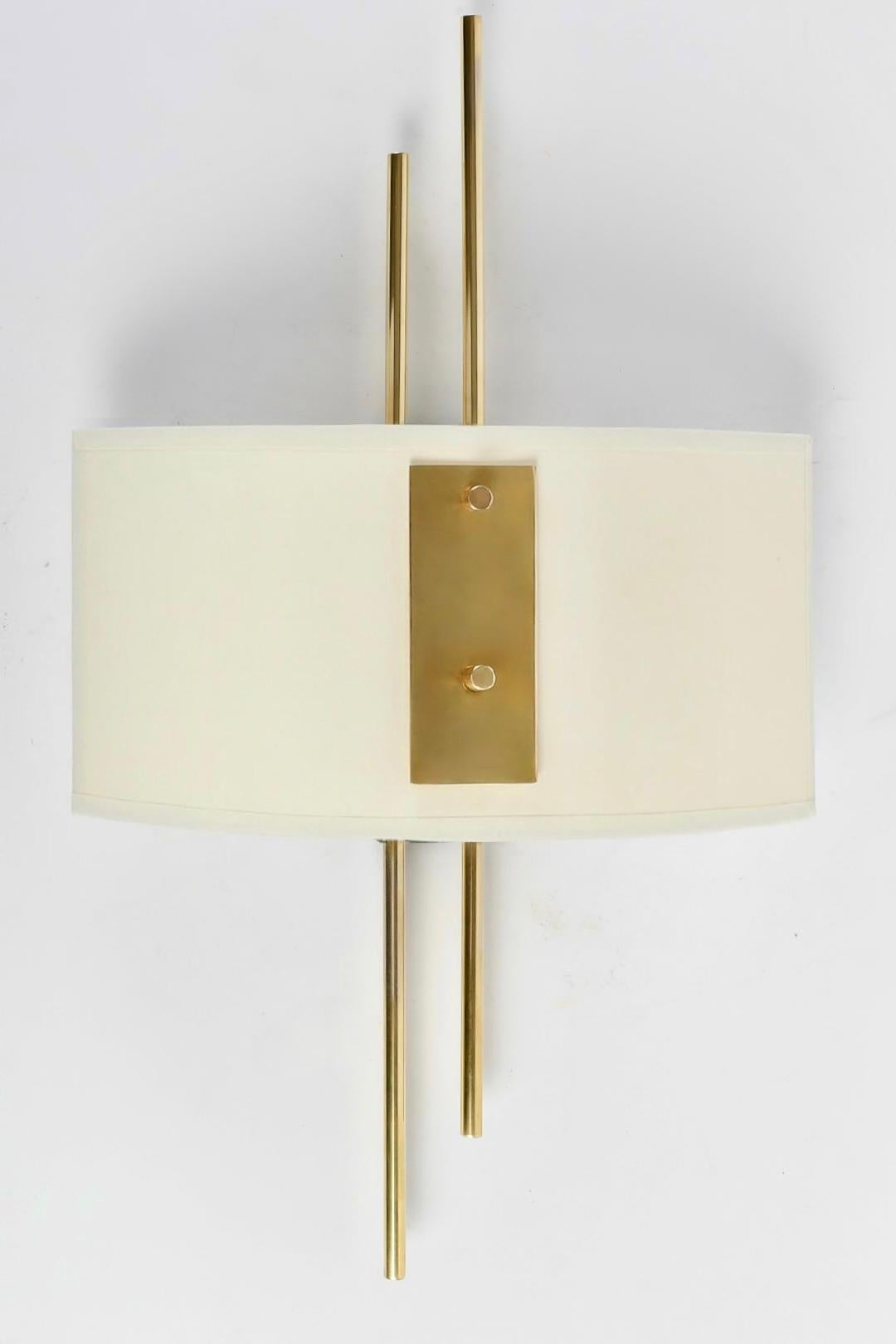 Composed of a wall support of rectangular shape in black wrought iron on which are placed two golden brass rods of round section placed vertically at two different heights.

On the front, they are dressed with a lampshade in the form of a perspex