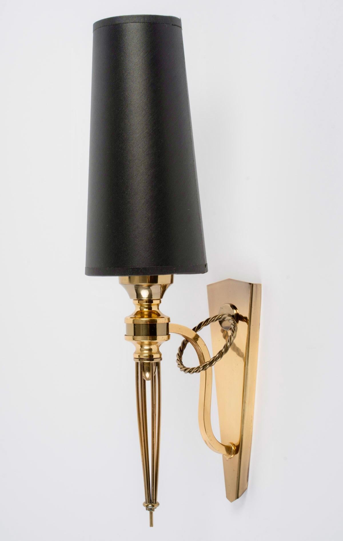 Compuesto por una placa de pared trapezoidal decorada con un magnífico anillo retorcido que sostiene el brazo de luz, 
En la parte inferior, una varilla de sección cuadrada que se eleva hacia arriba sostiene el brazo de la luz.
En su parte inferior,