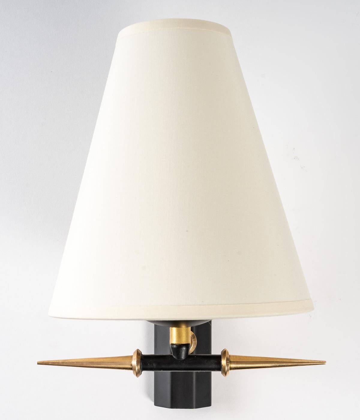 Composed of a wall support of rectangular form with cut sides of black color on which rests a small stem in gilded brass being used as support to the lampshade of off-white color of trapezoidal form and underlined of the base of a junction has