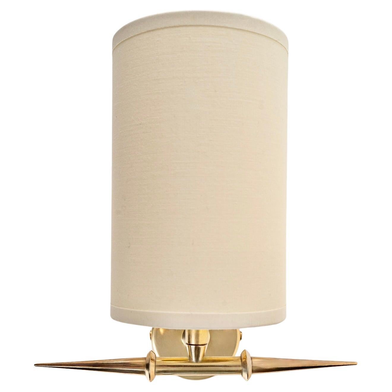 Composed of a round wall support in gilded brass on which rests a small rod in gilded brass serving as a support for the shade of off-white color of trapezoidal form.
The sconces are underlined at the base by a junction placed horizontally in