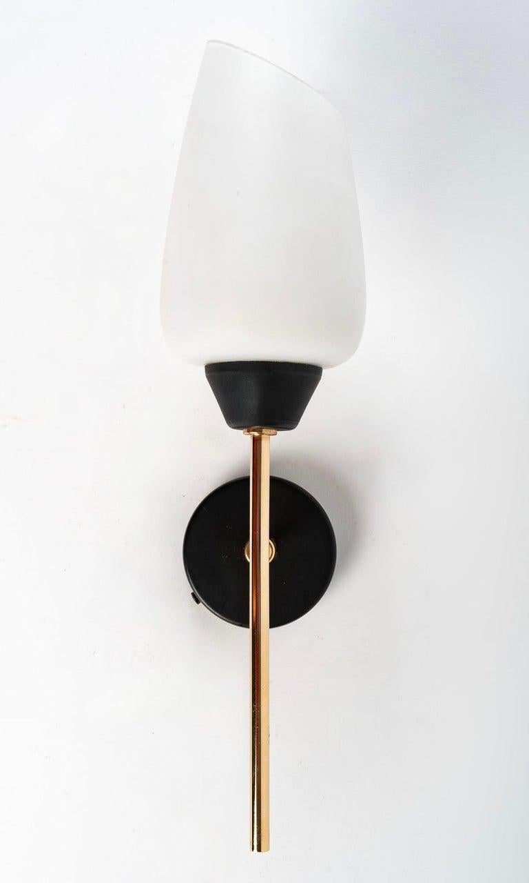 Composed of a wall support of round shape in blackened brass supporting a stem of round section in gilded brass dressed on the high part of an original opaline with cut edge on a side and underlined has its base of a cup in blackened brass.

1 bulb