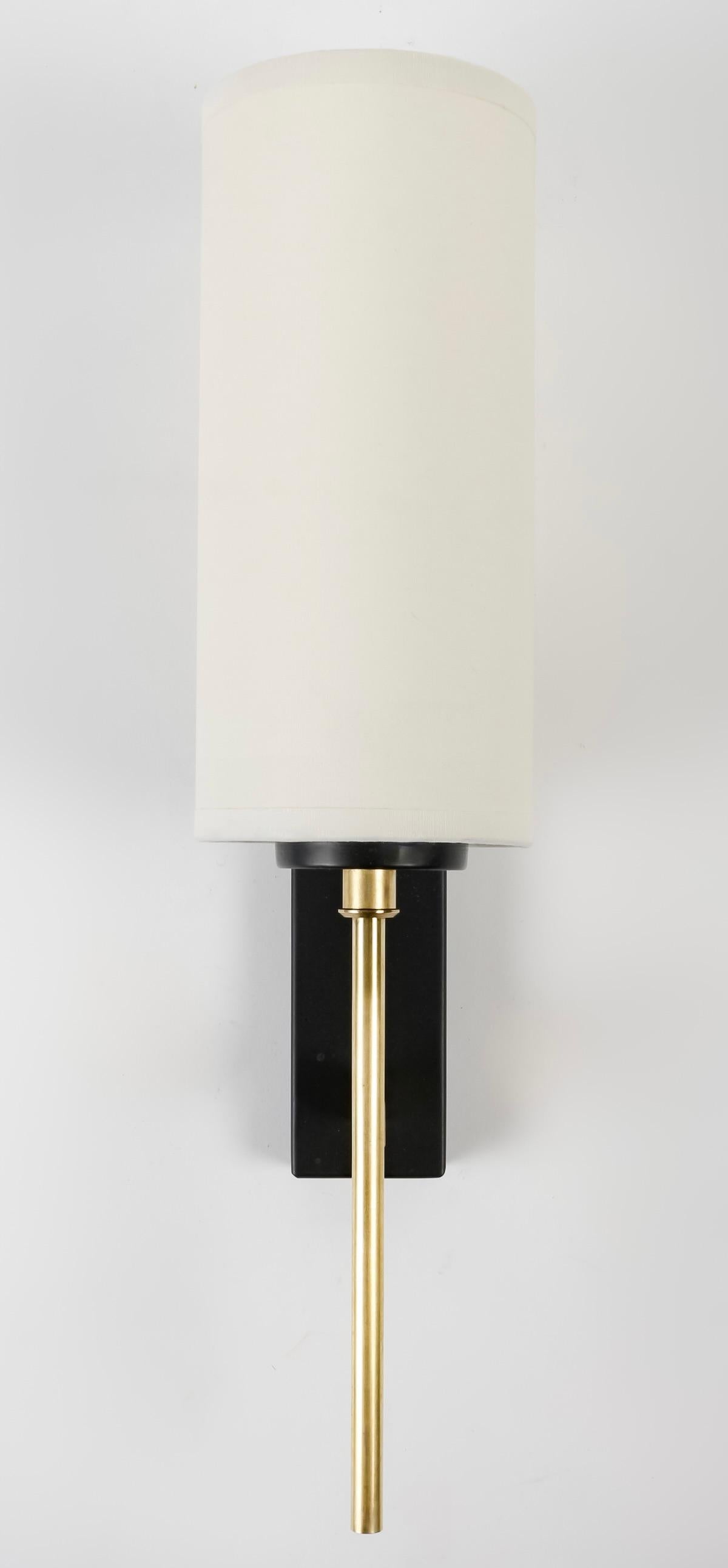 1950 Pair of Wall Lights Maison Lunel

Comprising a rectangular blackened brass wall plate supporting a round gilded brass stem, topped by a matching off-white cotton lampshade, highlighted at its base by a blackened brass cup.

1 bulb per sconce.