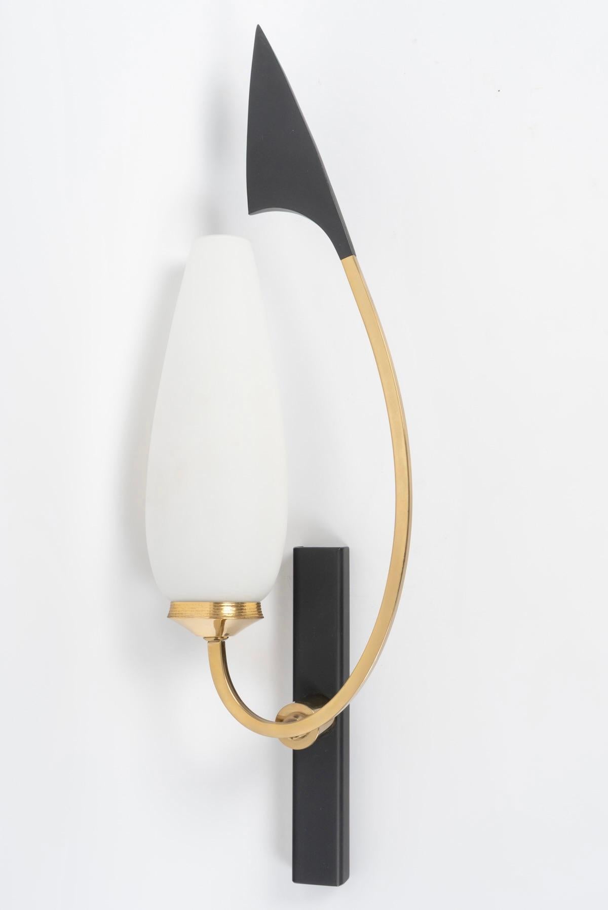 Besteht aus einer rechteckigen schwarzen Wandplatte, auf der ein kleiner Arm ruht, der einen quadratischen, nach oben gebogenen goldenen Messingstab trägt. Auf der einen Seite erhebt er sich und ist an der Spitze mit einem stilisierten schwarzen