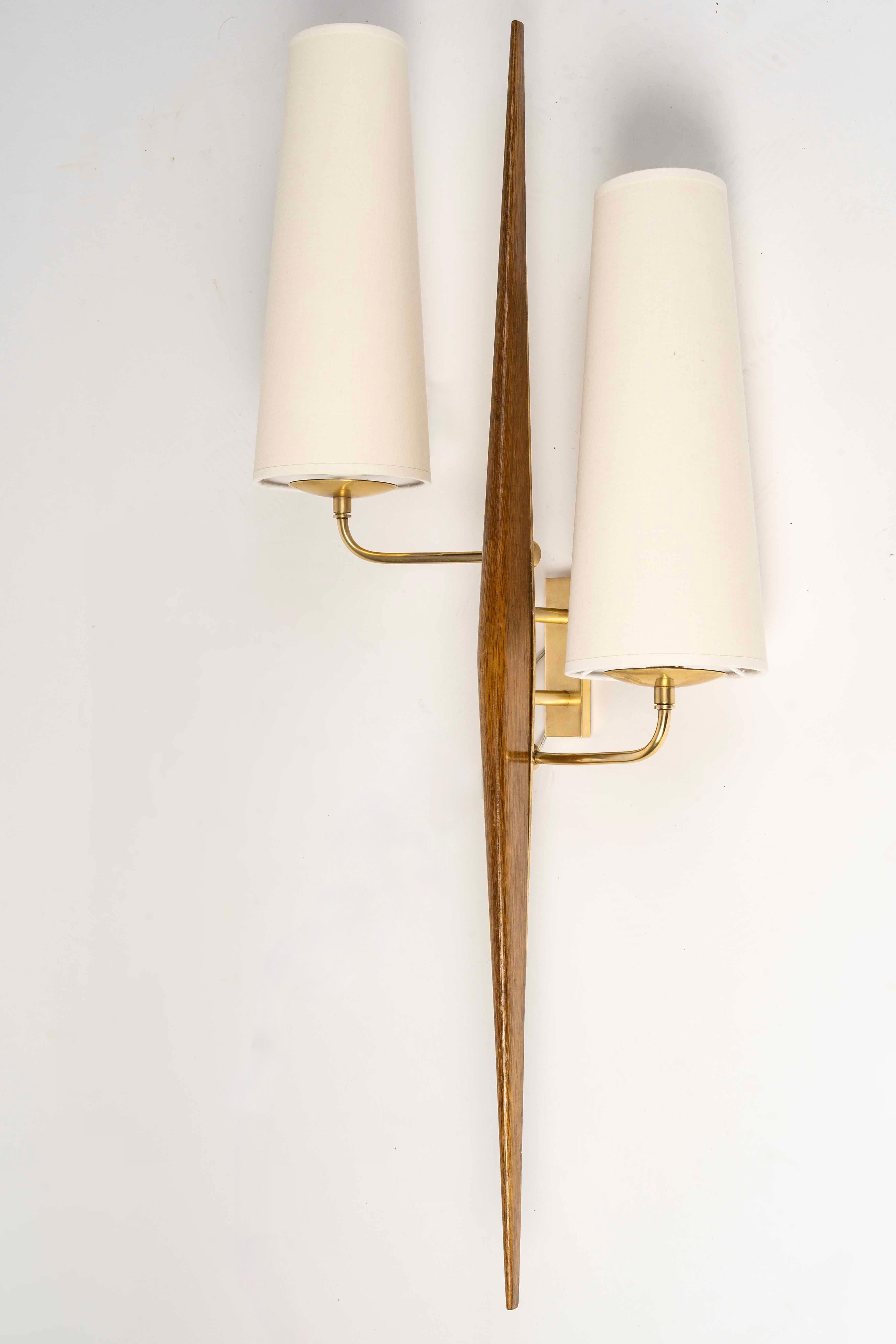Rare large pair of wall sconces by Maison Arlus

Composed of a central rod in gilded brass, decorated on the front with a stained wood spindle.
From the rectangular wall bracket at the back of the sconce, two light arms extend on either side of the