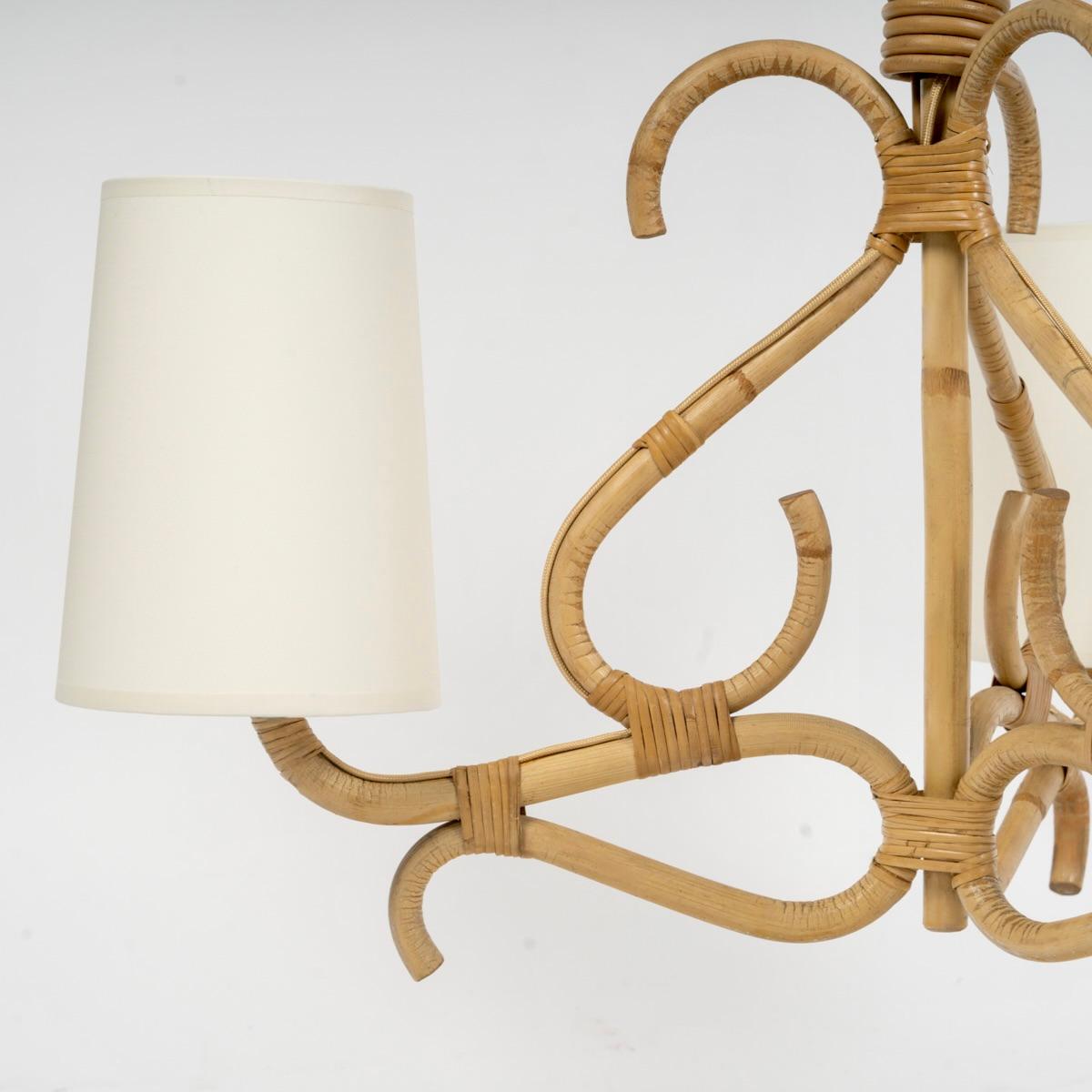 Composto da uno stelo centrale in rattan decorato con tre steli a forma di S distribuiti lungo il perimetro del lampadario.
Nella parte inferiore, tre steli di bambù curvi formano i bracci della lampada. Le loro estremità sono coperte da tre