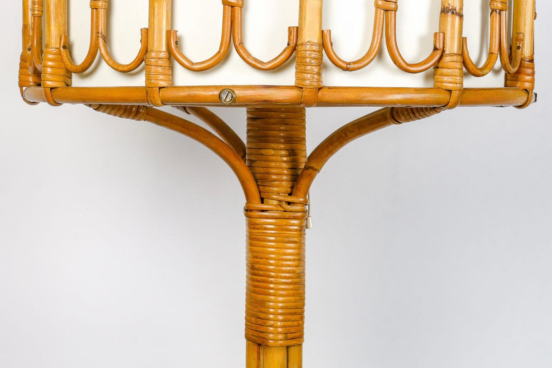 Composed of a central base formed by 4 rattan stems flared at the base, the 4 stems rest on a round base held by hoops, all made of rattan and linked together by thin rattan strips.
At the top, the central rod supports 4 rattan half-arches, on which