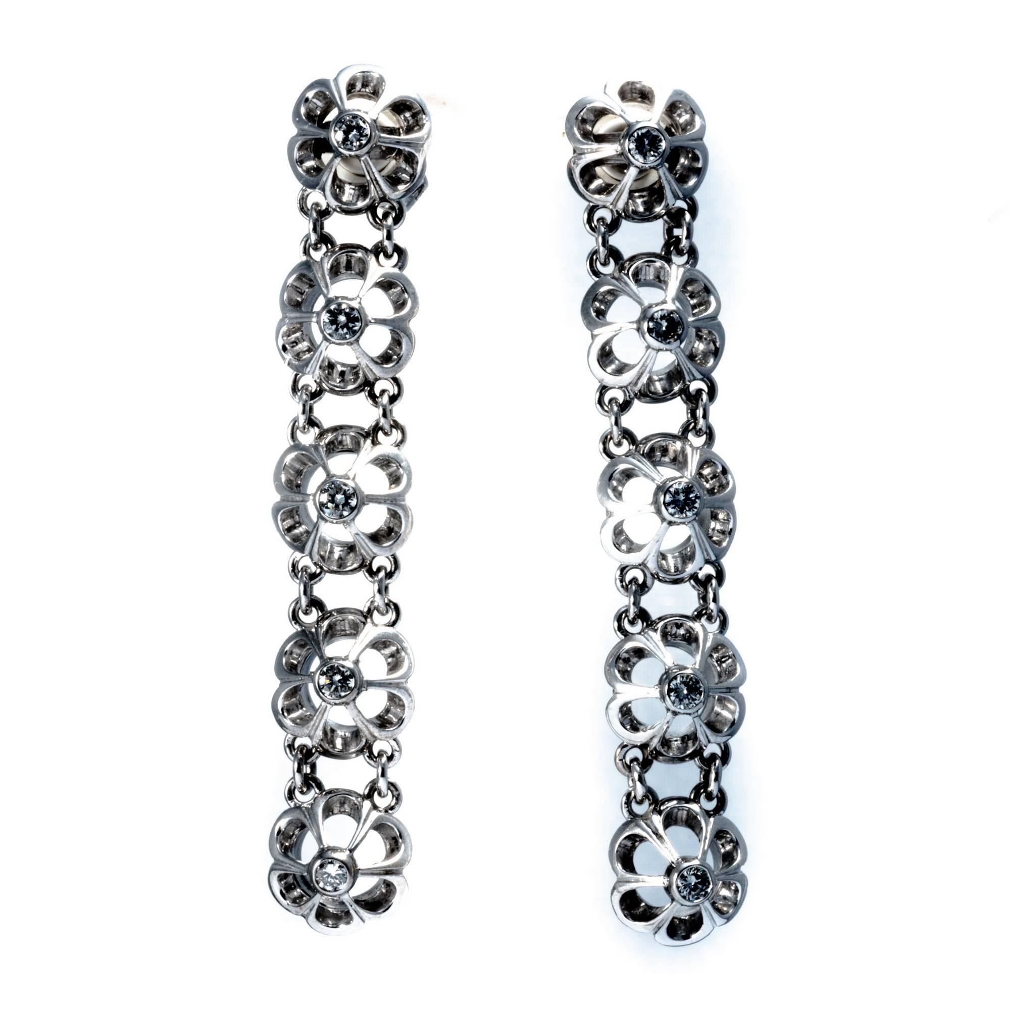 This retro dangle earrings handcrafted in white gold in the 1950's, feature 10 stylized flowers, each of which is enlightened by a diamond at the centre. Approximate diamond total weight is carats 0.60