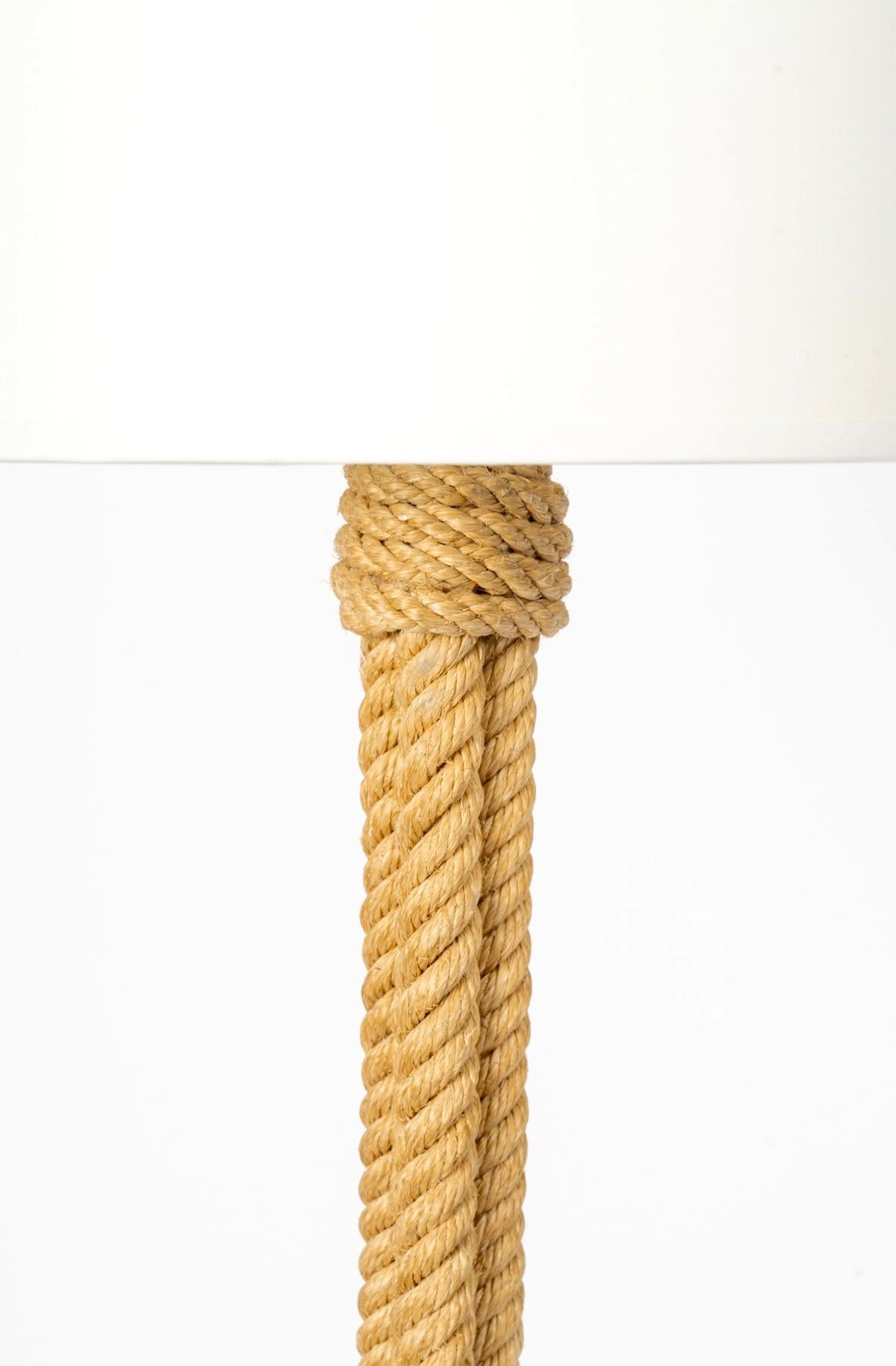 Composed of a central shaft resting on 3 high feet distributed around the perimeter of the central shaft, all made of rope.
It is covered with a large cylindrical lampshade in identically redone white cotton.
1 bulb.

Adrien Audoux and Frida Minet