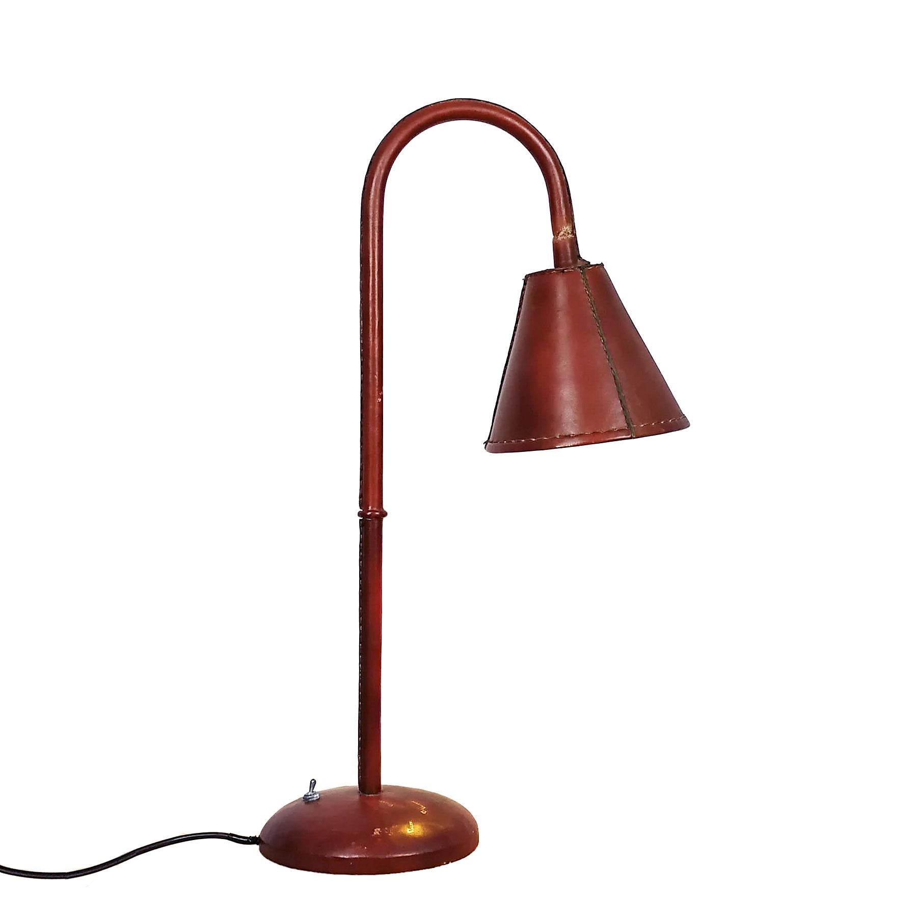 Large table lamp, metal completely sheathed with red leather, adjustable lampshade by a ball joint under the leather. Steel base for stability.
Maker: Valentí (Hot iron golden stamp in base)

Spain, Barcelona, circa 1950.