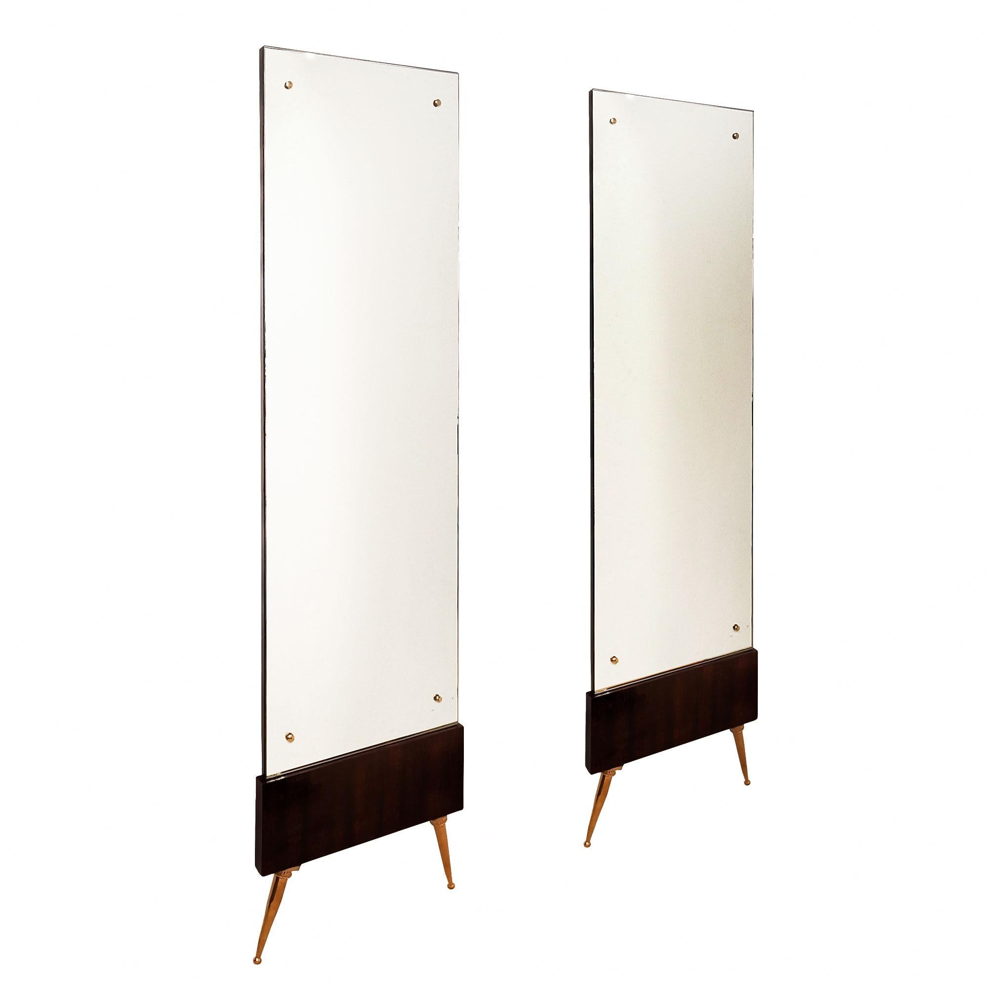 Pair of tall mirrors with a solid wood back, stained and French polished mahogany base, polished brass feet and screw covers.

Italy c. 1950.