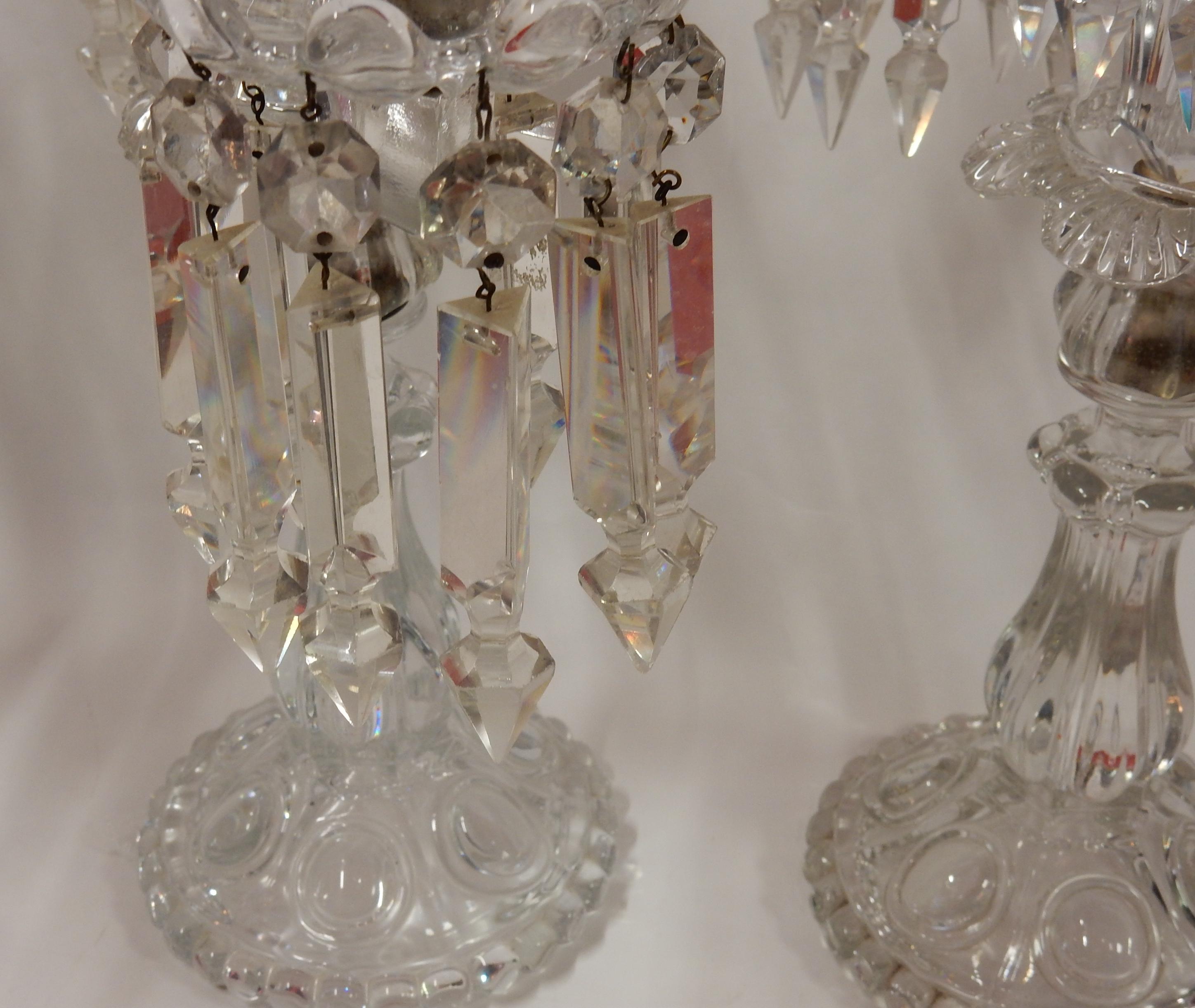 Serie of 4 crystal candlesticks with 2 arms with prismatic cut pendants with a step to end in a point, round base decorated with bumps and round pearls. Signed Baccarat, 3 signed in relief and one with engraved stamp, when it’s signed, its authentic
