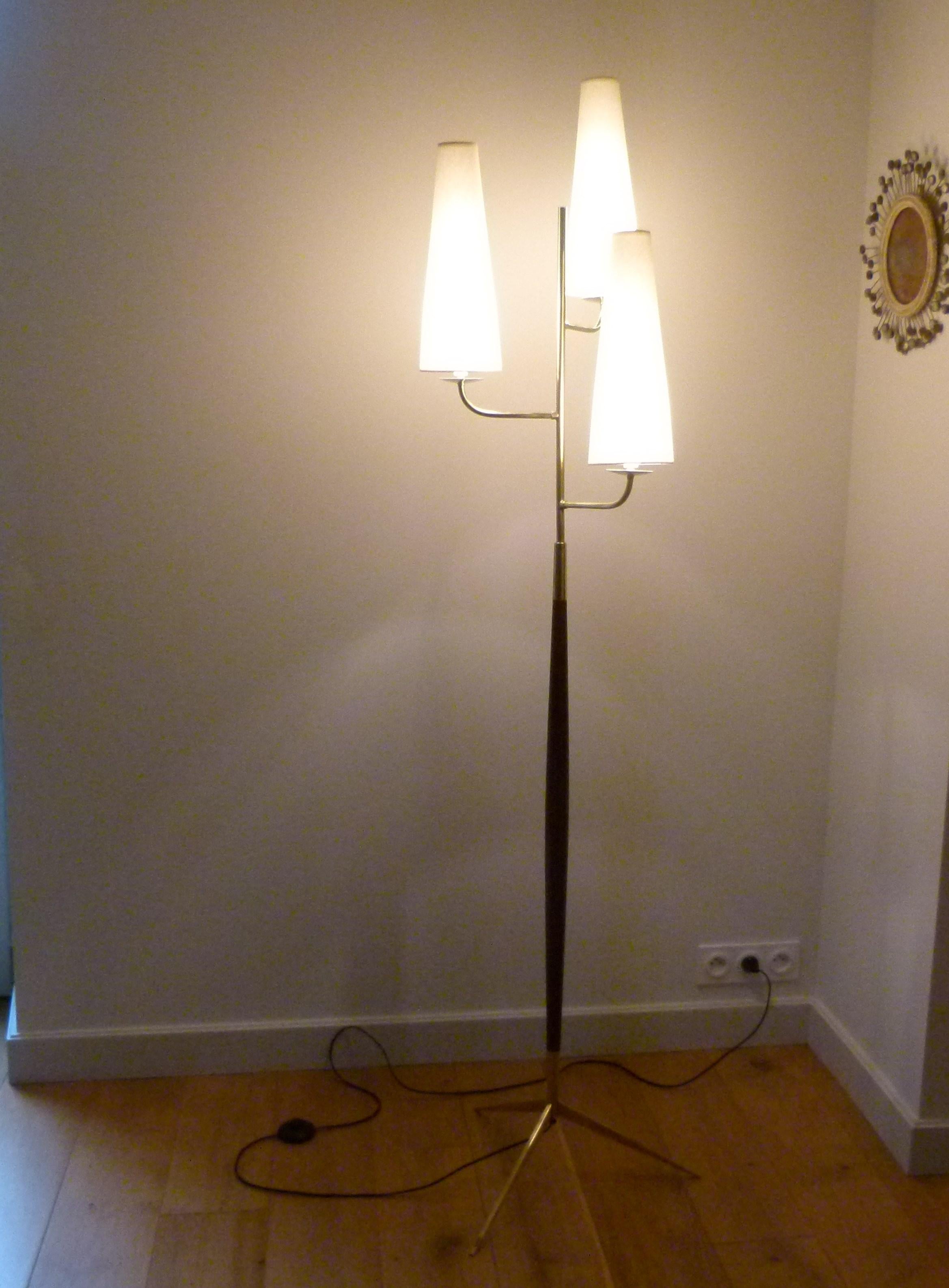 Triple light floor lamp consisting of a solid brass tripod foot on which is placed a conical trunk in varnished mahogany, on both sides of which are placed brass sconces.
On each arm is placed a conical shaped shade, diffusing the light.
This