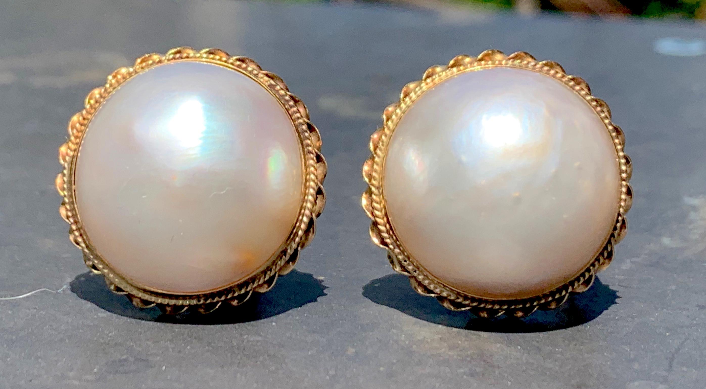 This elegant and wearable pair of ear clips features wonderful and large mabé pearls. The pearls are set in 14 karat yellow gold and decorated with a twisted gold wire border.