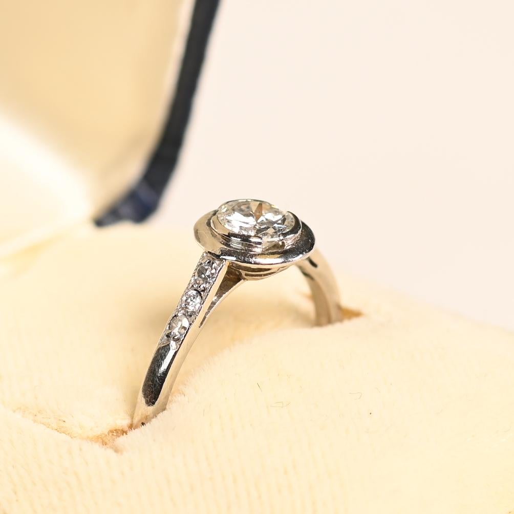 Uno splendido anello di fidanzamento vintage francese, meticolosamente realizzato a mano in platino nel 1950 circa, con un diamante rotondo taglio brillante da 0,5 carati circa di colore I e purezza VS1. La pietra centrale è circondata da un