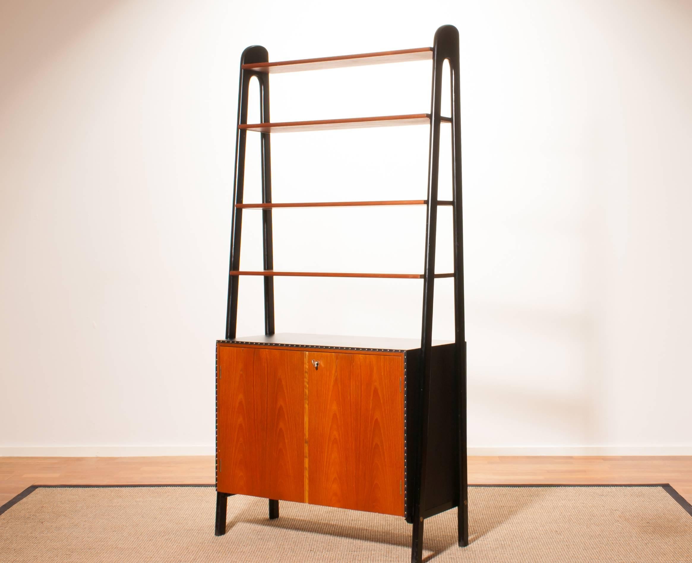 Beautiful bookcase by Bertil Fridhagen for Bodafors, Sweden.
This cabinet is made of teak and cupboard is upholstered with black leatherette.
Behind the doors there is an extendable writing top with a drawer.
It is in an excellent