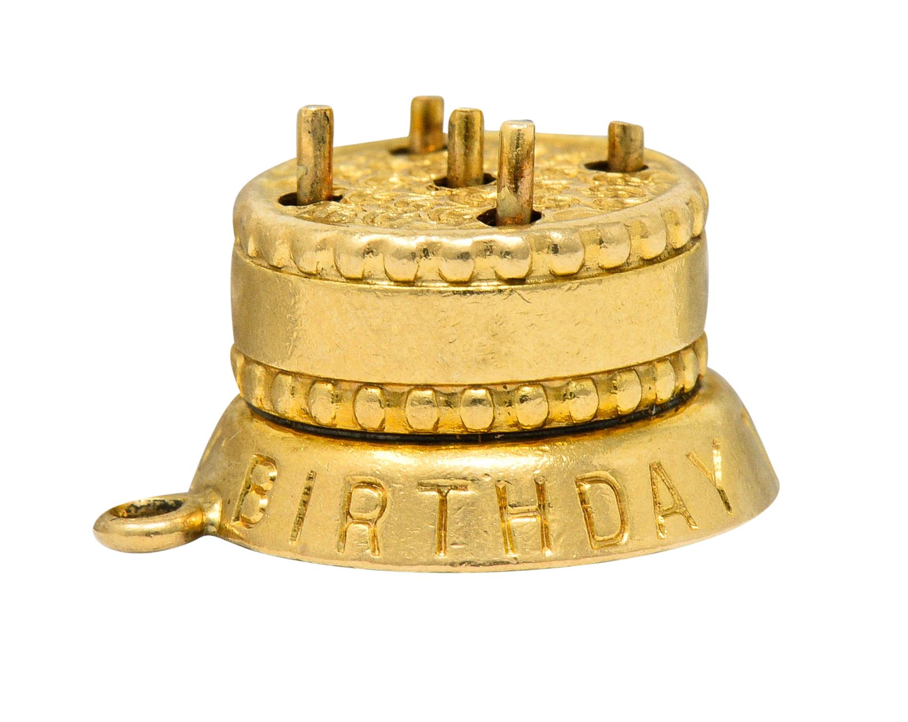 Charm is designed as a circular cake with deeply engraved swirled frosting

Cake stand is inscribed 'Happy Birthday To You'

With a lever at base that can be pushed to reveal five hidden candles

Stamped 14K for 14 karat gold

Circa: