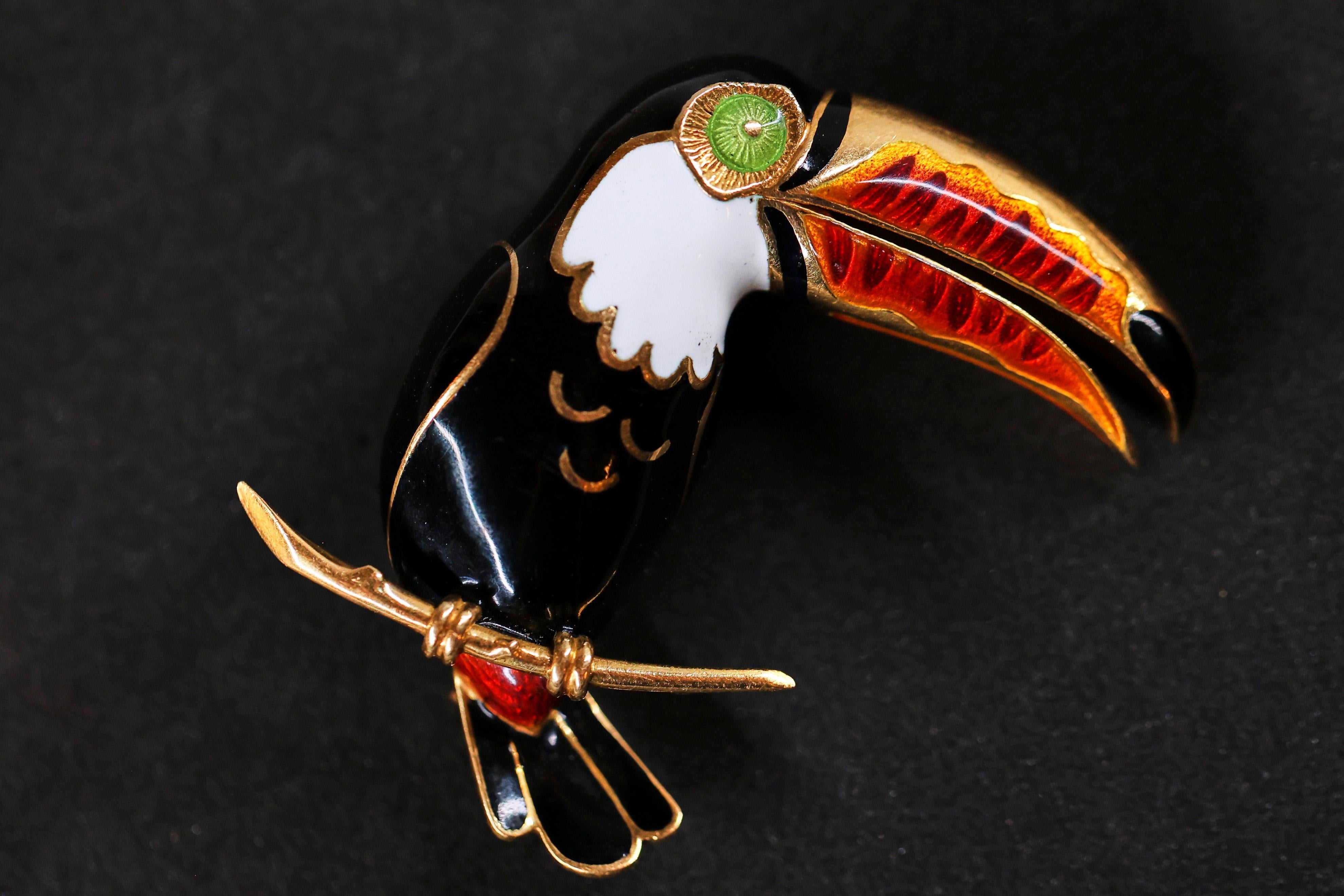 A beautiful gold and enamel toucan brooch. The brooch is adorned with enamel throughout on 18 carats yellow gold. The brooch is fitted with a double pin clasp and safety catch.

Solid gold 750/000
41 x 35 mm
16.14 grams

