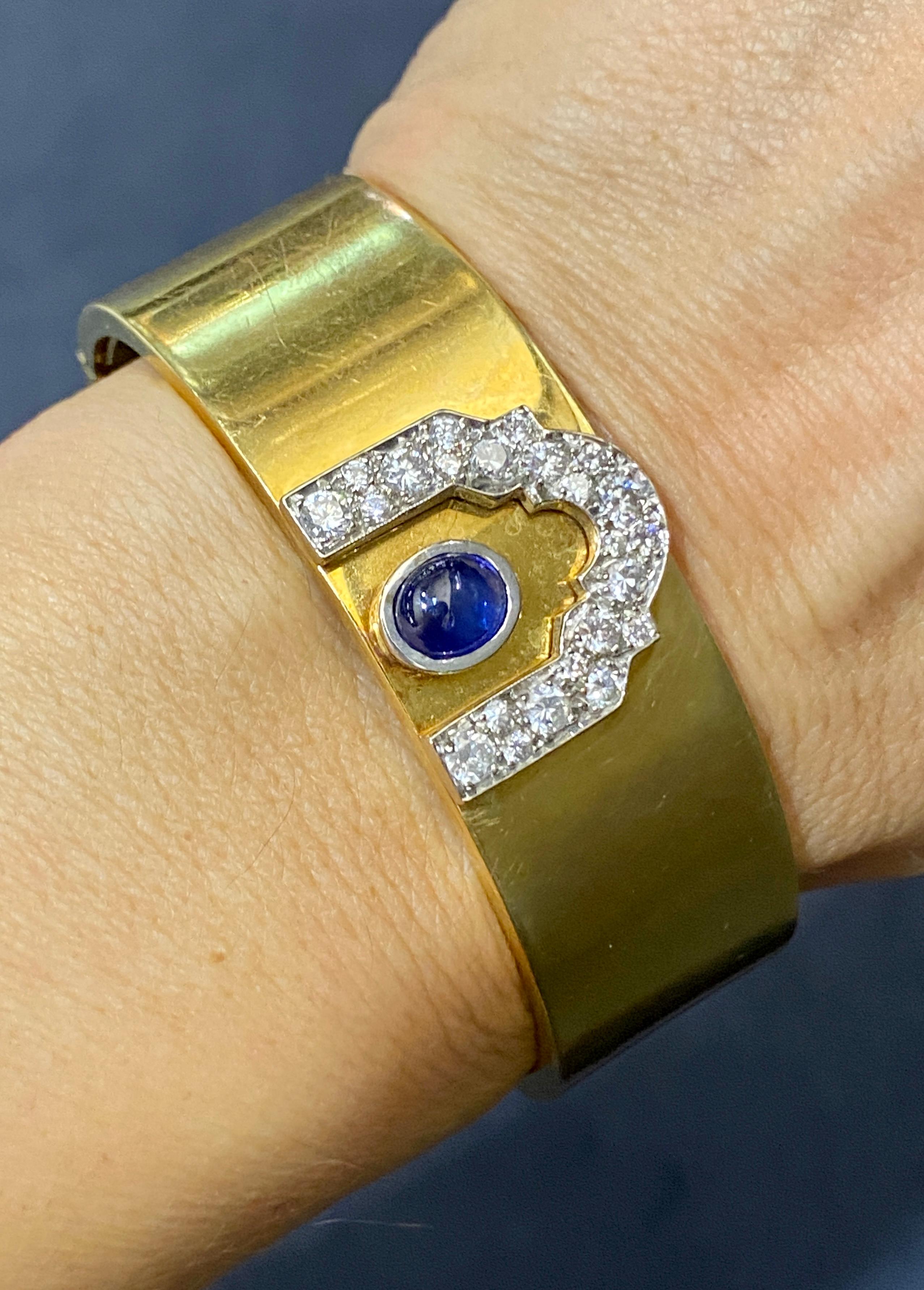 Cette manchette en or 18k des années 1950 est ornée d'environ 1,2 carats de diamants ronds et de 1 carat de saphir cabochon. Il s'agit d'une pièce lourde qui est très confortable à porter. La manchette est munie d'une charnière qui permet de
