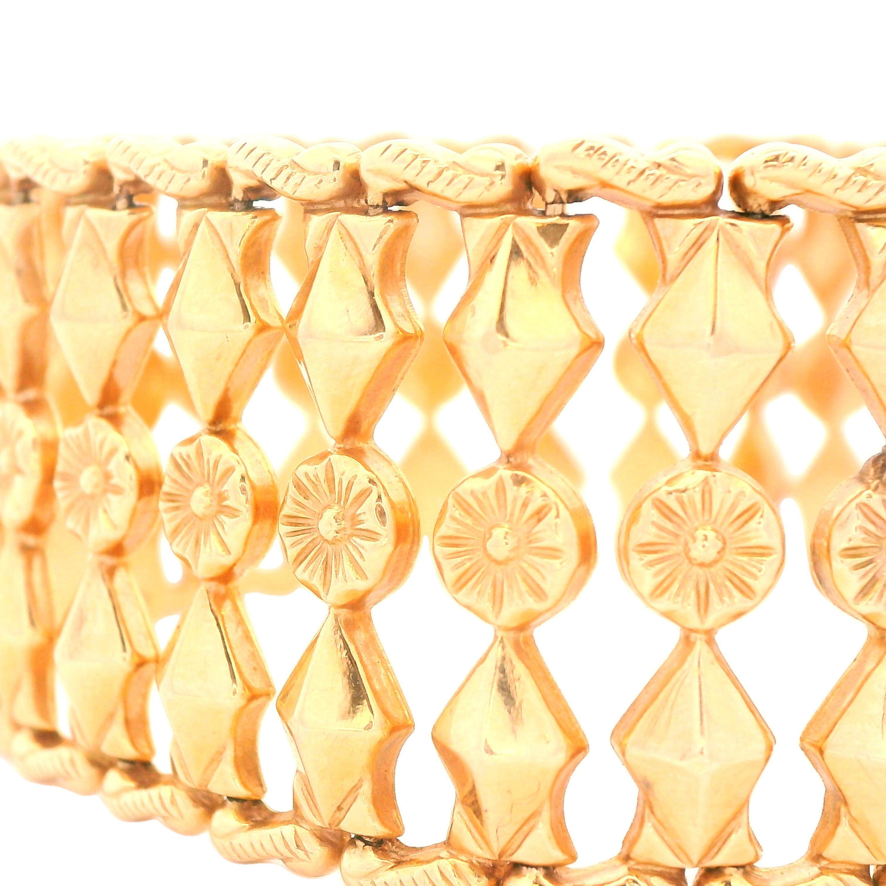 Questo splendido bracciale a maglie fantasia risale agli anni '50 ed è realizzato in oro giallo 18 carati. Questo bracciale utilizza lo spazio negativo per creare un design a maglie fantasia con una fila centrale. I bordi del bracciale sono incisi