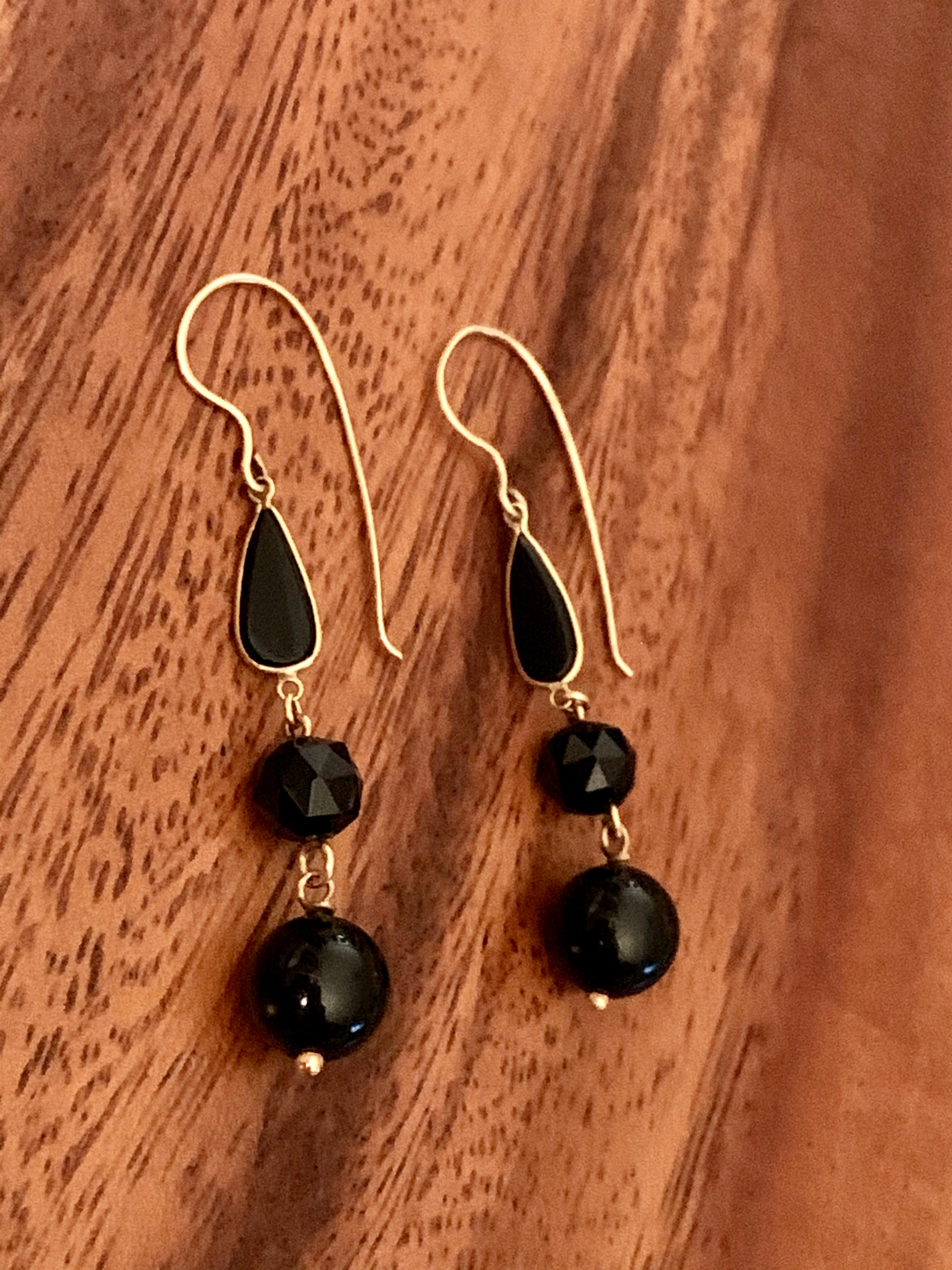 These 1950-1960's era vintage earrings feature three black Onyx stones in each earring.  One is a faceted bead, one is smooth and one is teardrop-shaped with a 14 karat Gold frame. The ear wires and findings are all 14 karat Gold as well.  
Length: