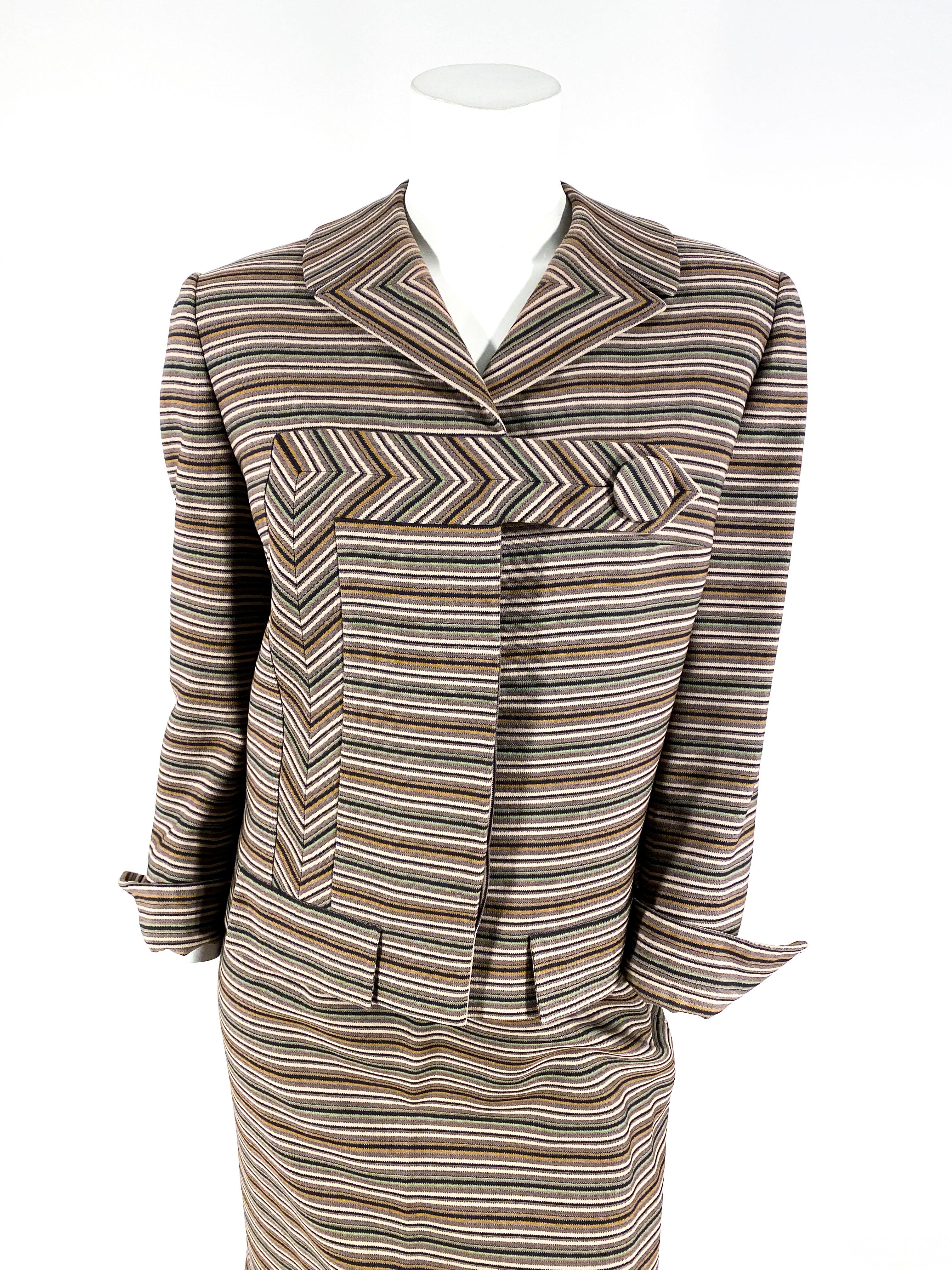 Late 1950s to early 1960s Irene suit made of a wool blend striped textile featuring tones of olive, sage, black, and taupe. The Jacket has inset and pattern-matched panels, decorative pocket coverings, and a large asymmetrical button closure. The