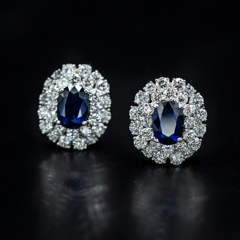 Mid-Century Royal Blue oval sapphire and round brilliant-cut diamond cluster clip-on earrings in platinum and 18kt white gold, French import marks, 1950s/1960s. Each of the earrings features an oval sapphire of a royal blue color in an open-back