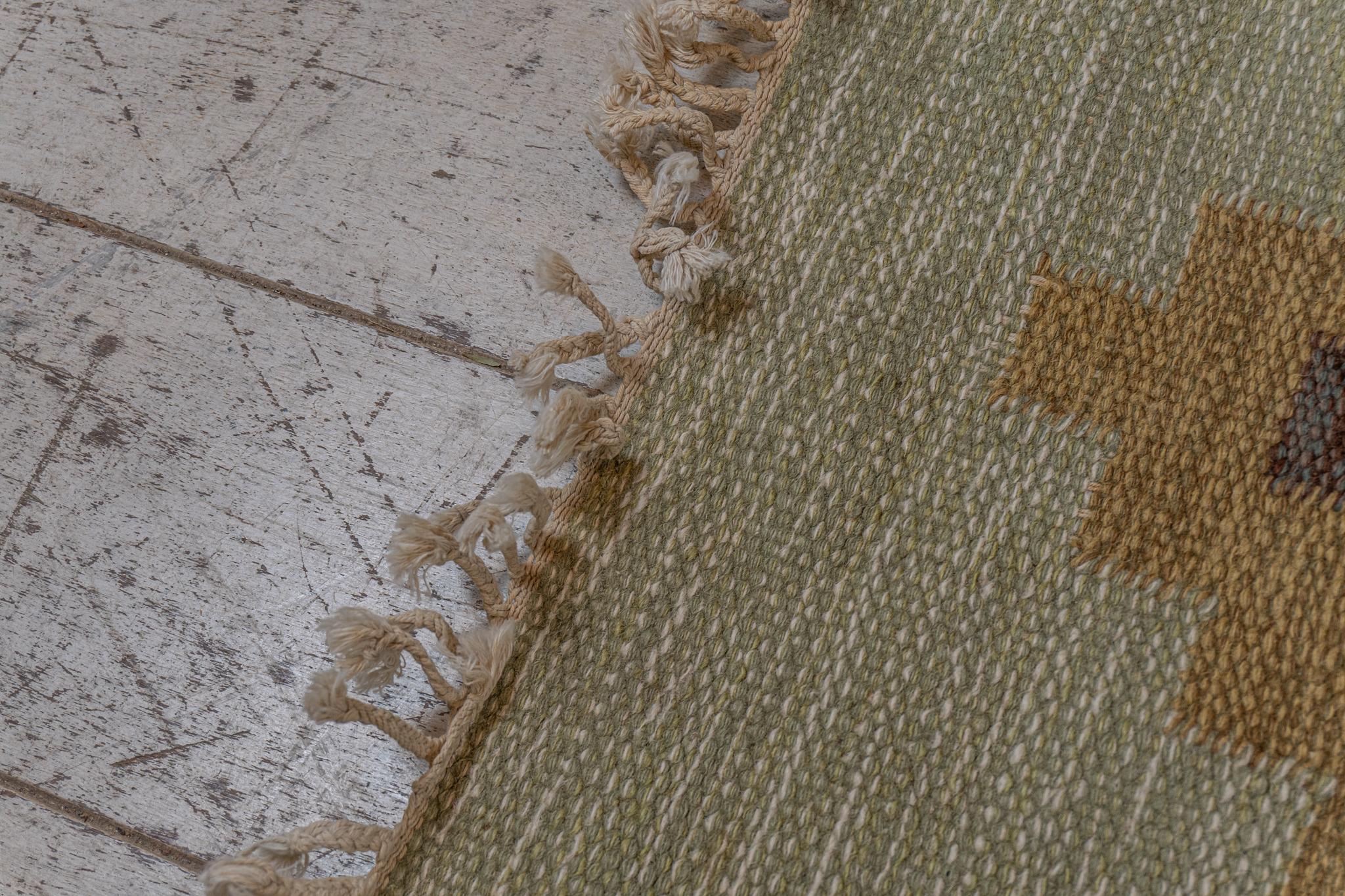 A 1950/60s Swedish flat weave rug initialled with the insignia IR Ida Rydelius. IDA was a well-known textile artist recognised for her unusual and fabulous designs.

The rug features a lovely, muted, sage-green, background. Overlaid is a design of