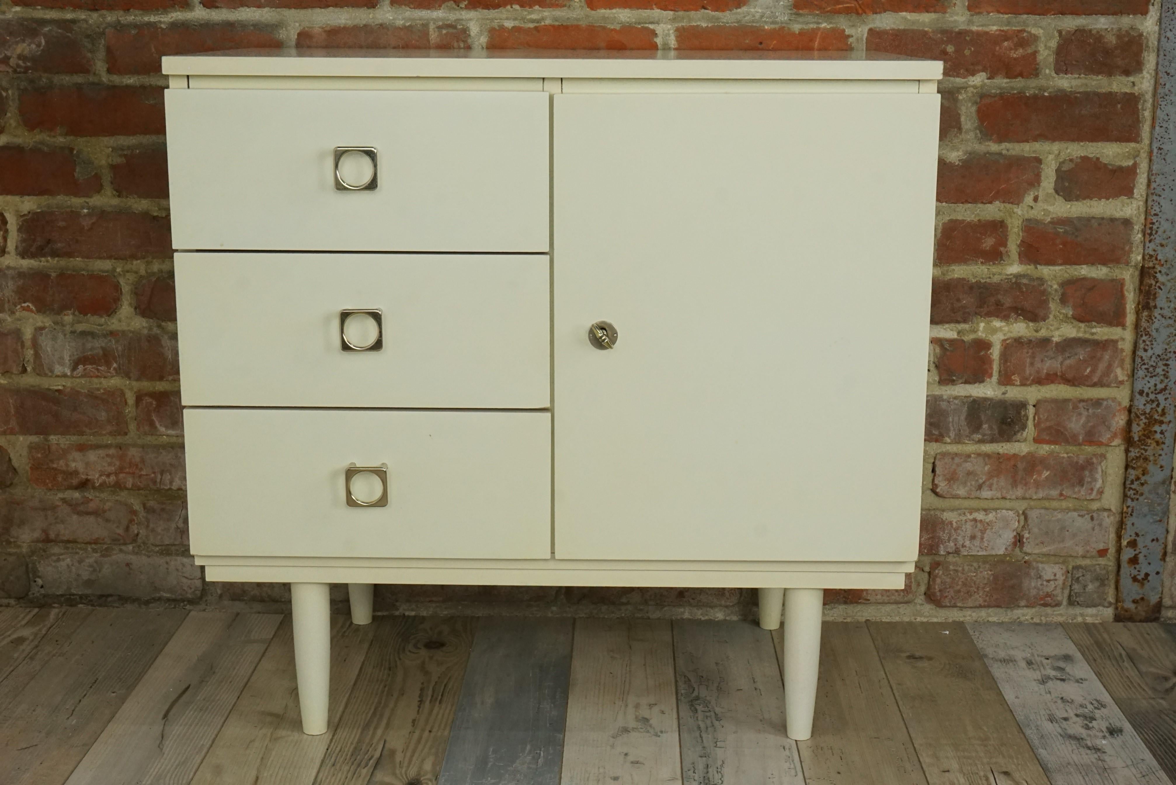 1950s-1960s Warm White Satin Wooden Cabinet composed of a wooden structure with minimalist and sober lines, chrome metal square handles and compass feet ; harmonious design and practical.