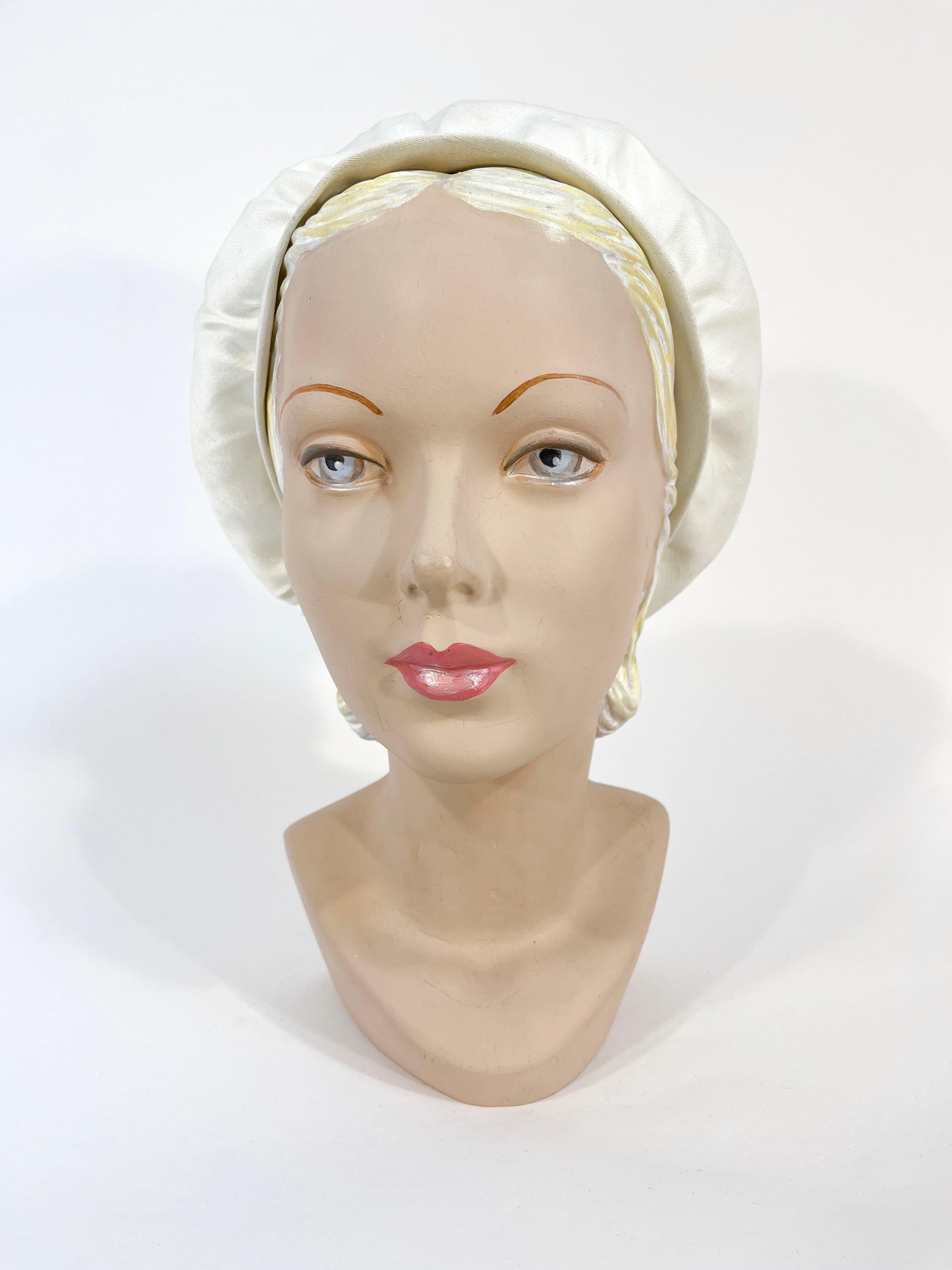 Late 1950s to early 1960s White Raw Shantung silk tam with large gathers centering a handmaid double tassel. The bottom of the hat has a band of matching silk providing some shape to the base of the hat. The interior is unlined and has a grow grain