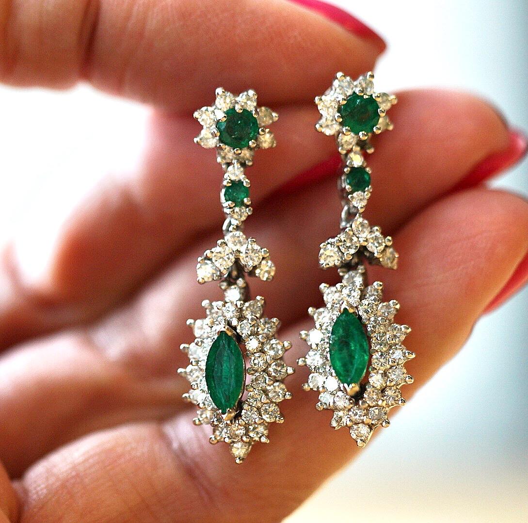 1950s Retro Floral motif Diamond, Emerald and 14K White Gold Drop Earrings. 4 hinged segments maximize shine and add a playful element! The post segment features a round emerald surrounded by an 8-diamond halo. A round emerald flanked top and bottom