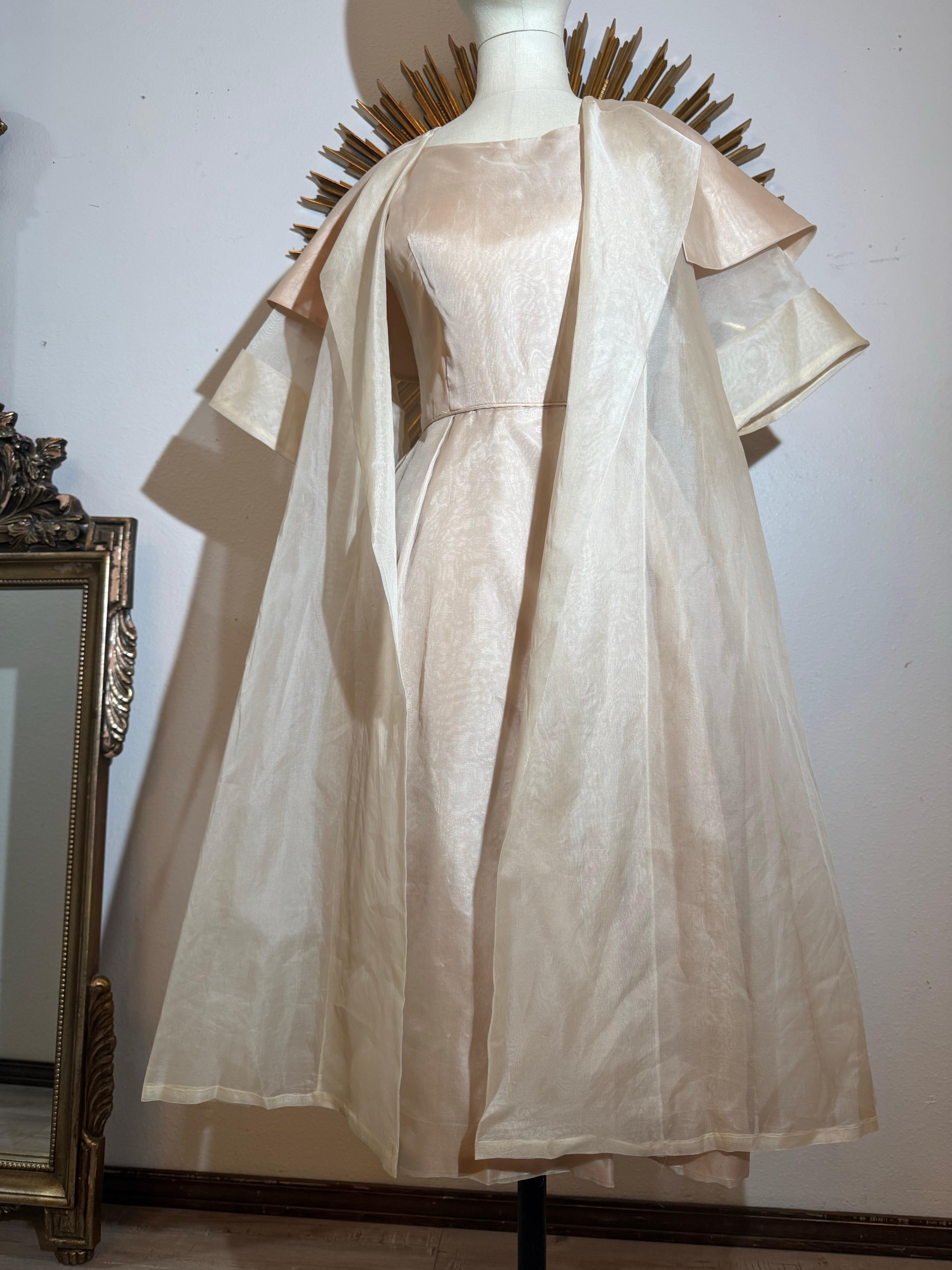 Eleanor Gay 2 pezzi degli anni '50: abito in organza di media lunghezza e cappotto trasparente con ampio colletto in taffetà:  Stile a tubino con una profonda piega in vita sul davanti a sinistra. L'abito è completamente foderato con sottogonna in