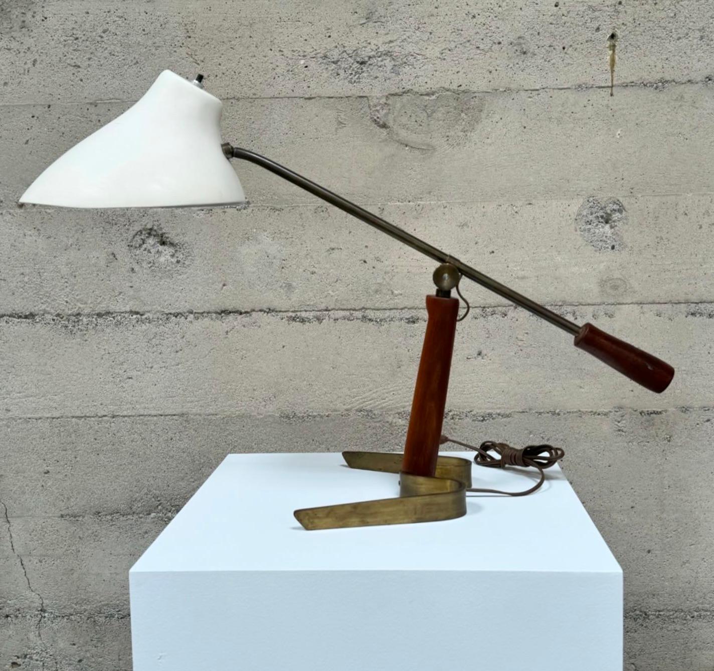 Adjustable Dutch table lamp with a ribbon brass base with a sculptural fiberglass shade and a wooden counterweight handle along with a wooden stem with a brass knob to tighten the adjustable arm. The main stem is set on an angle and gives the