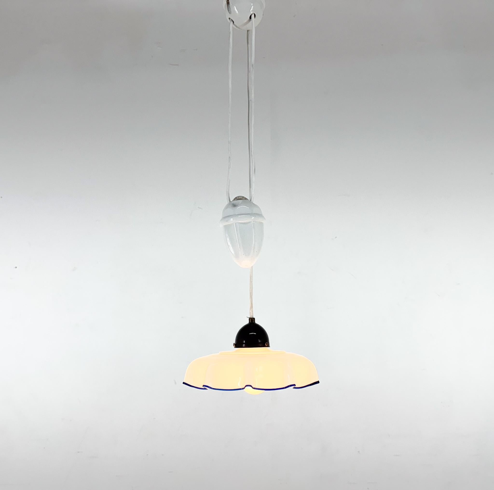 Lampada a sospensione del Mid-Century realizzata in vetro al latte, ceramica e bachelite. L'altezza è regolabile da 75 cm a 135 cm. 
Prodotto nell'ex Cecoslovacchia. 
Nuovo cablaggio. 
Lampadina: 1 x E 26 / E 27. 
Compatibile con il cablaggio degli