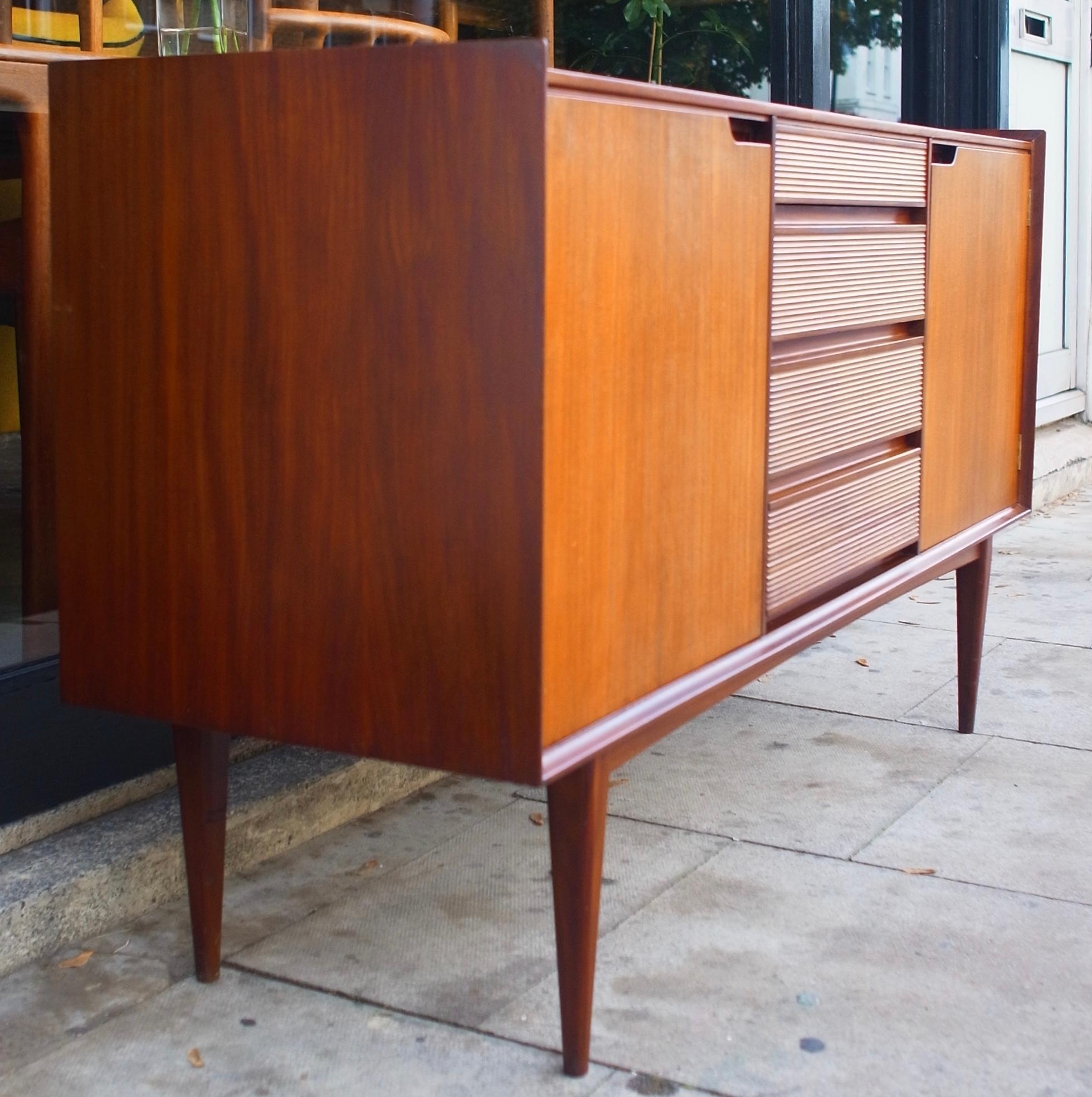 British mid-century Afromosia Teak Sideboard by Richard Hornby for Fyne Ladye in the 1960s and retailed through Heals. Superb craftsmanship throughout, carved from solid from Afrormosia with beautiful cutaway handle detail, reeded drawer fronts and