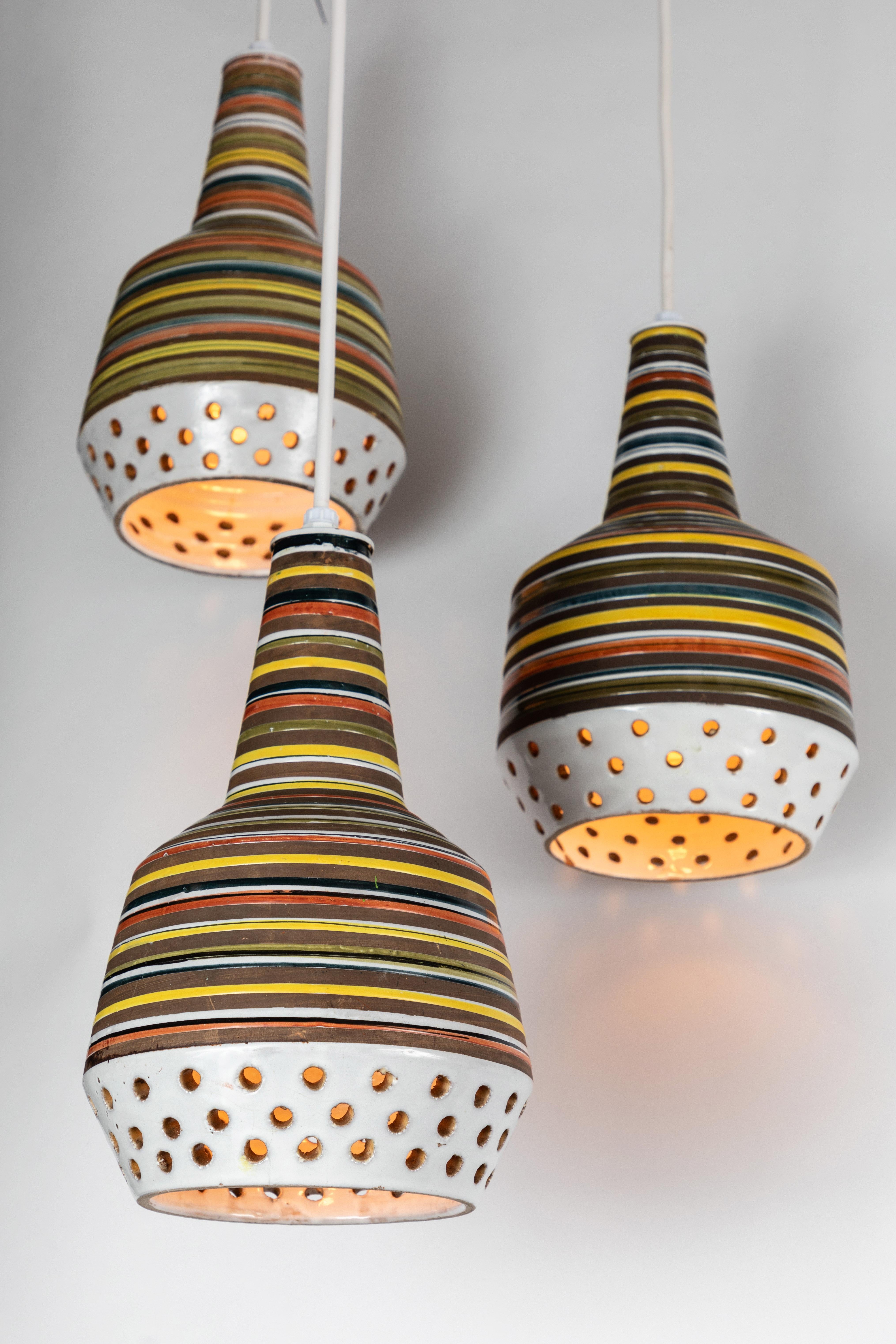 1950s Aldo Londi ceramic Bitossi pendant lamp for Italian Raymor. This rare and sculptural Italian ceramic lamp is executed with multicolored glazed horizontal stripes and geometric circular perforations.

Please note, two lamps available.

Ceramic