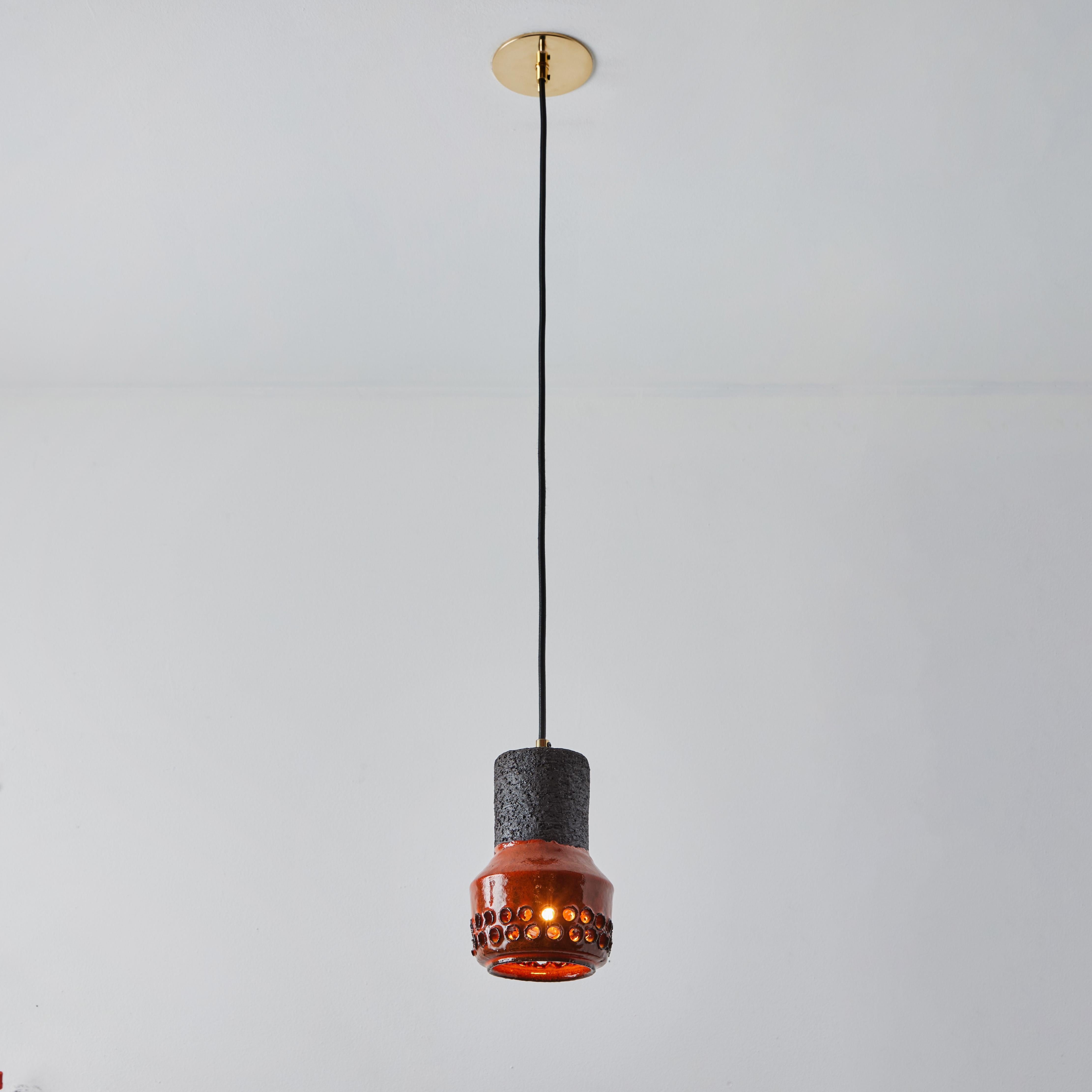 Lampe à suspension Bitossi en céramique Aldo Londi des années 1950 pour le Raymor italien. Cette lampe rare et sculpturale en céramique italienne est exécutée dans une glaçure auburn chaude avec des perforations circulaires géométriques. 

Convient