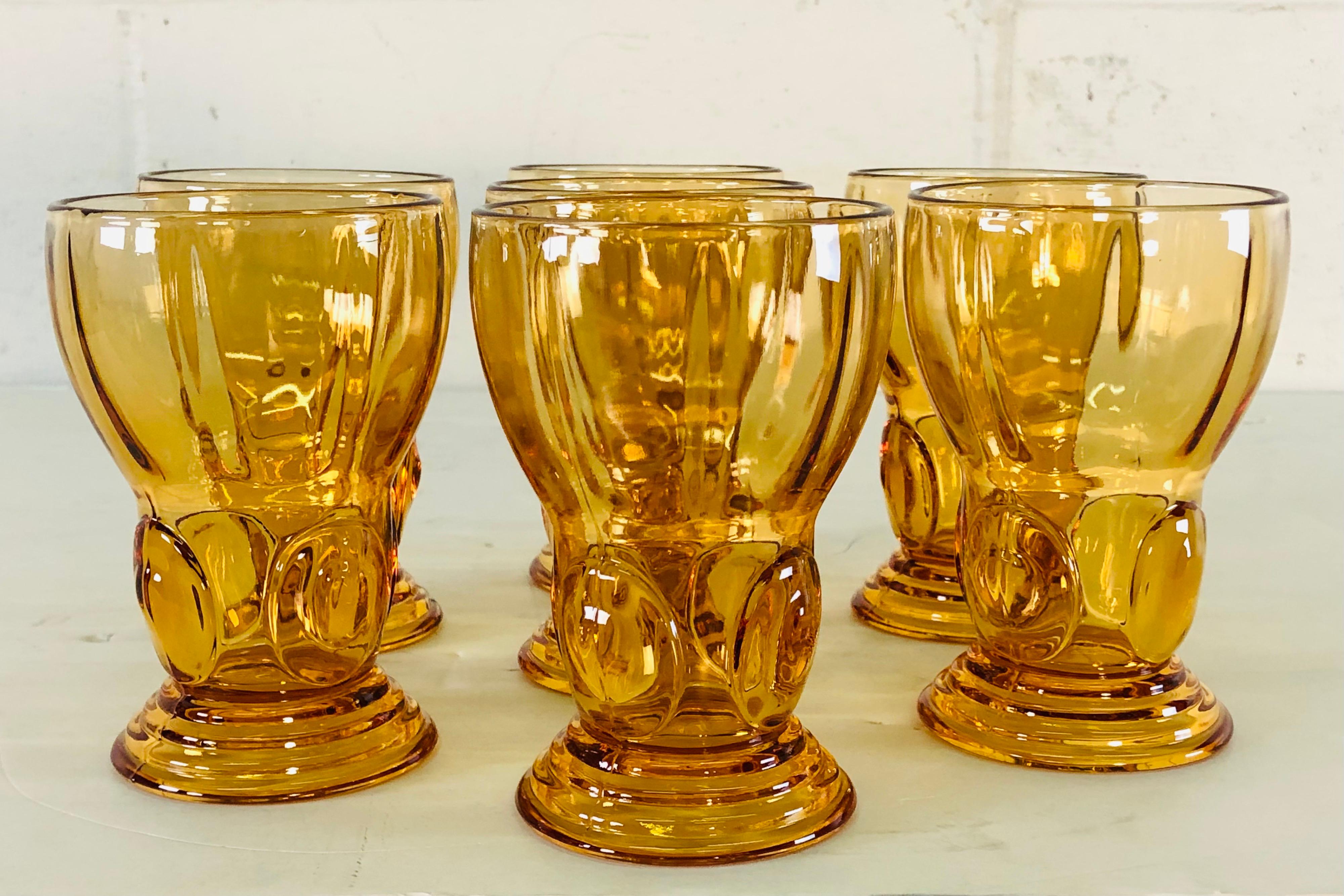 Vintage 1950s set of seven amber glass tall tumblers with drops of glass on the stems. Unmarked.