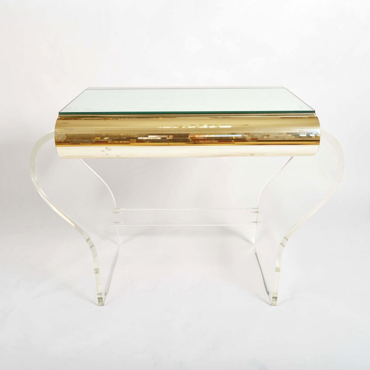 Hollywood Glamour.
Cool, smooth luxury from California. 1950’s clear Lucite mirror and gold dressing-table.
The two-sided mirrored top opens up for maximum reflection and the gold striped central drawer allows added room for cosmetics and bijou.