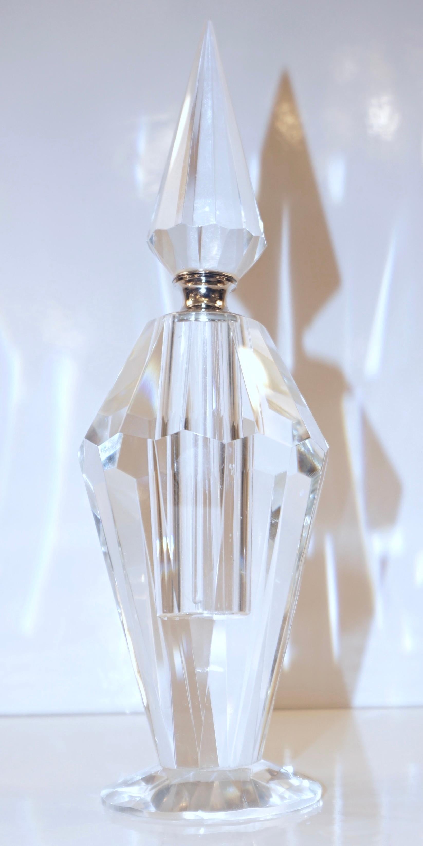 This elegant and sophisticated perfume bottle, a high-quality crystal product with Art Deco flair, and Hollywood Regency glamour, with a prismatic geometric pyramid shape, resembles a diamond for its multiple faceted cuts in the body, the base, and