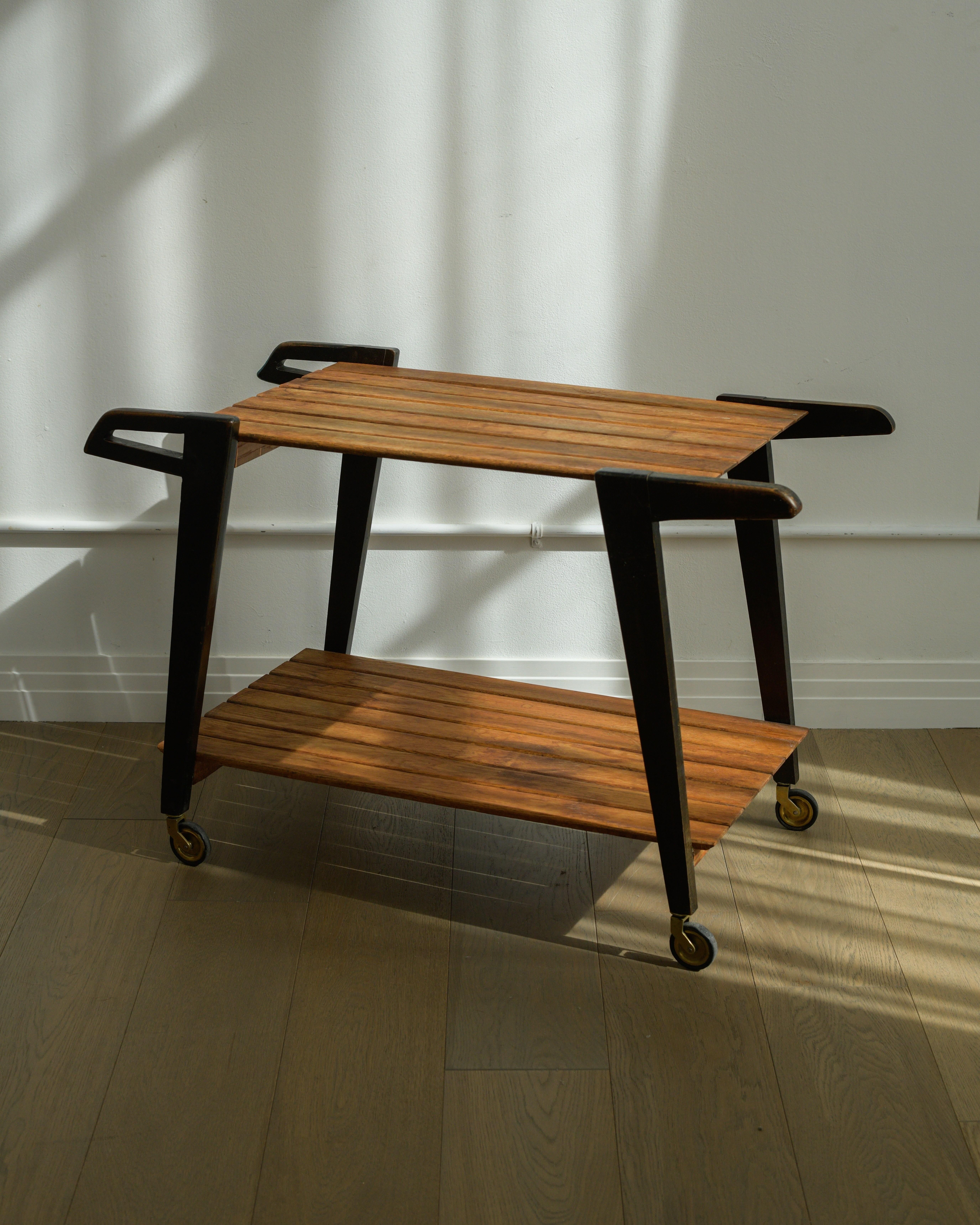 1950s André Paccard Serving cart, Produced by Atelier Andre Paccard, France.

In good vintage condition with age commensurate patina. Water marks and scattered staining to wood slats. Rolls nicely. 

Oak, ebonized wood. 
24.25