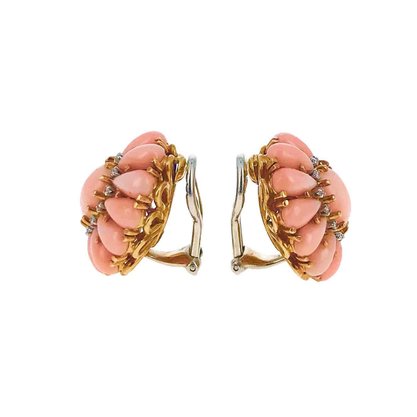 This pair of ear clips features oval cabochon angel skin coral surrounded by tear drop shaped cabochon coral and accented with round diamonds. The clip earrings are mounted in 18 karat yellow gold and were made circa 1950.