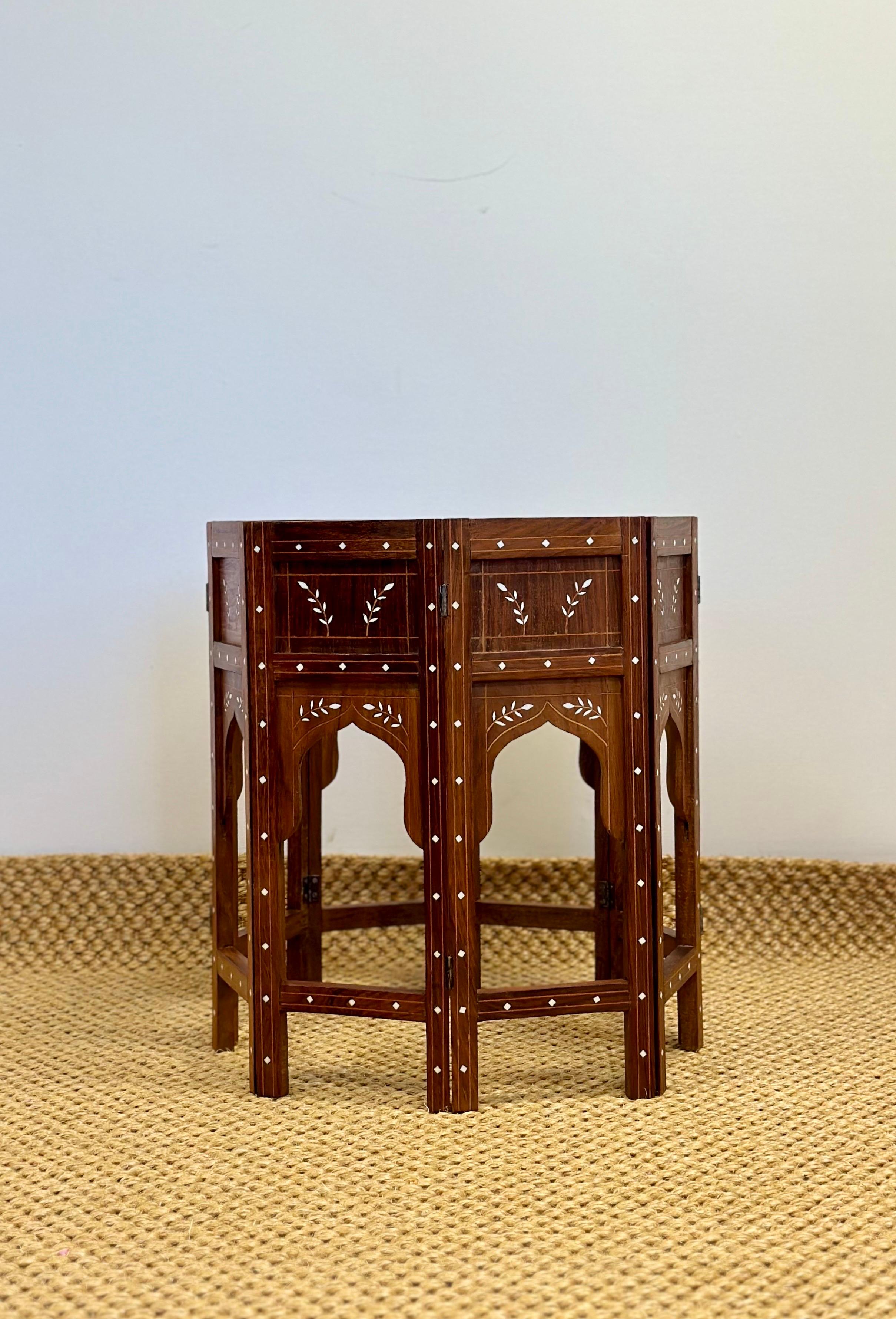 Wir freuen uns sehr, einen exquisiten Beistelltisch aus den 1950er Jahren anbieten zu können.  Dieser Tisch ist ein wunderschönes Zeugnis feiner Handwerkskunst. Er ist aus massivem Holz handgefertigt und weist eine komplizierte Knocheneinlage auf,