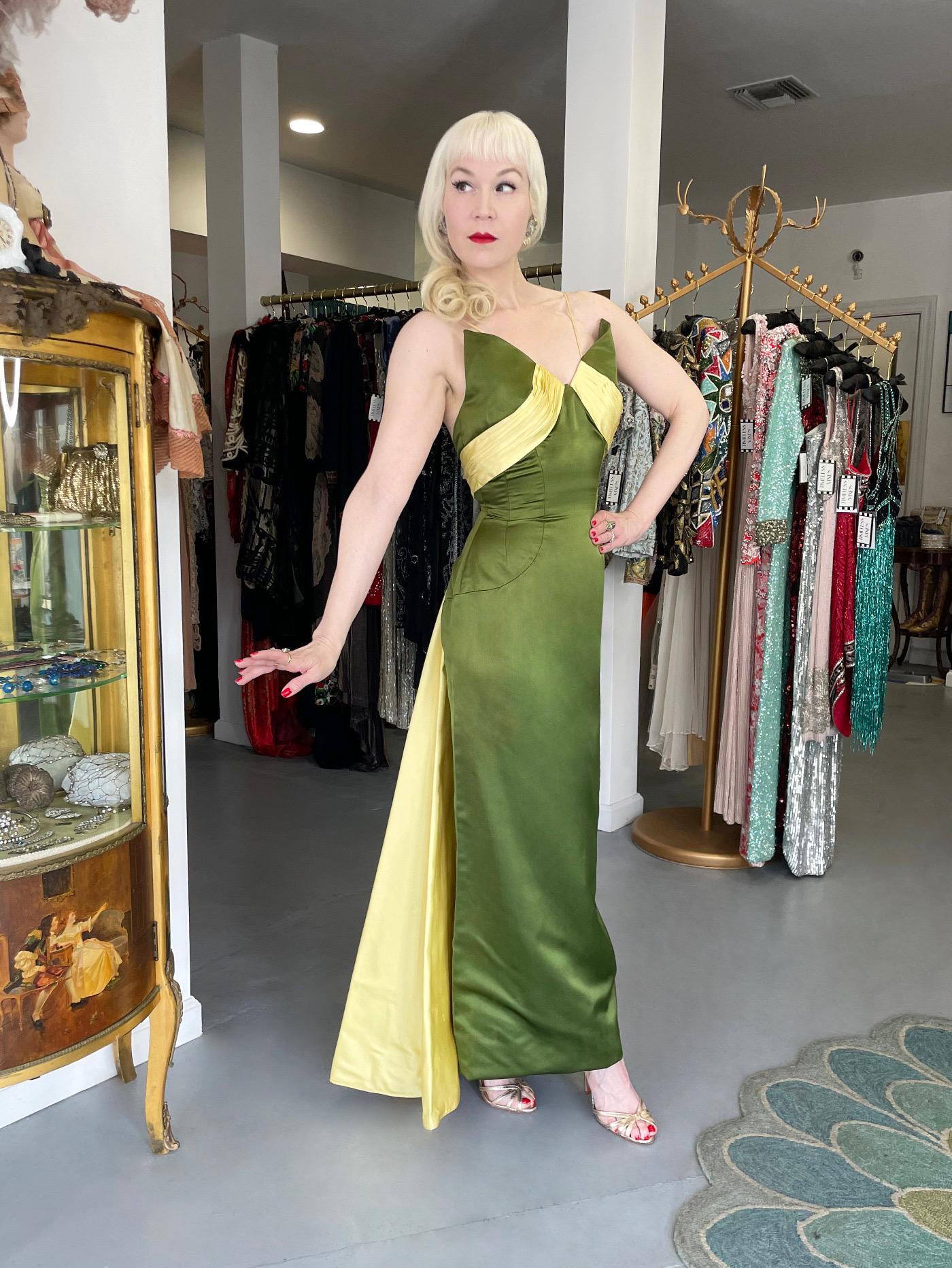 An absolutely gorgeous 1950's olive green and yellow silk satin gown designed by Anne Verdi of New York. The flawless nipped-waist hourglass silhouette with luxurious fabric has the sophisticated elegance the 1950's were known for. The construction