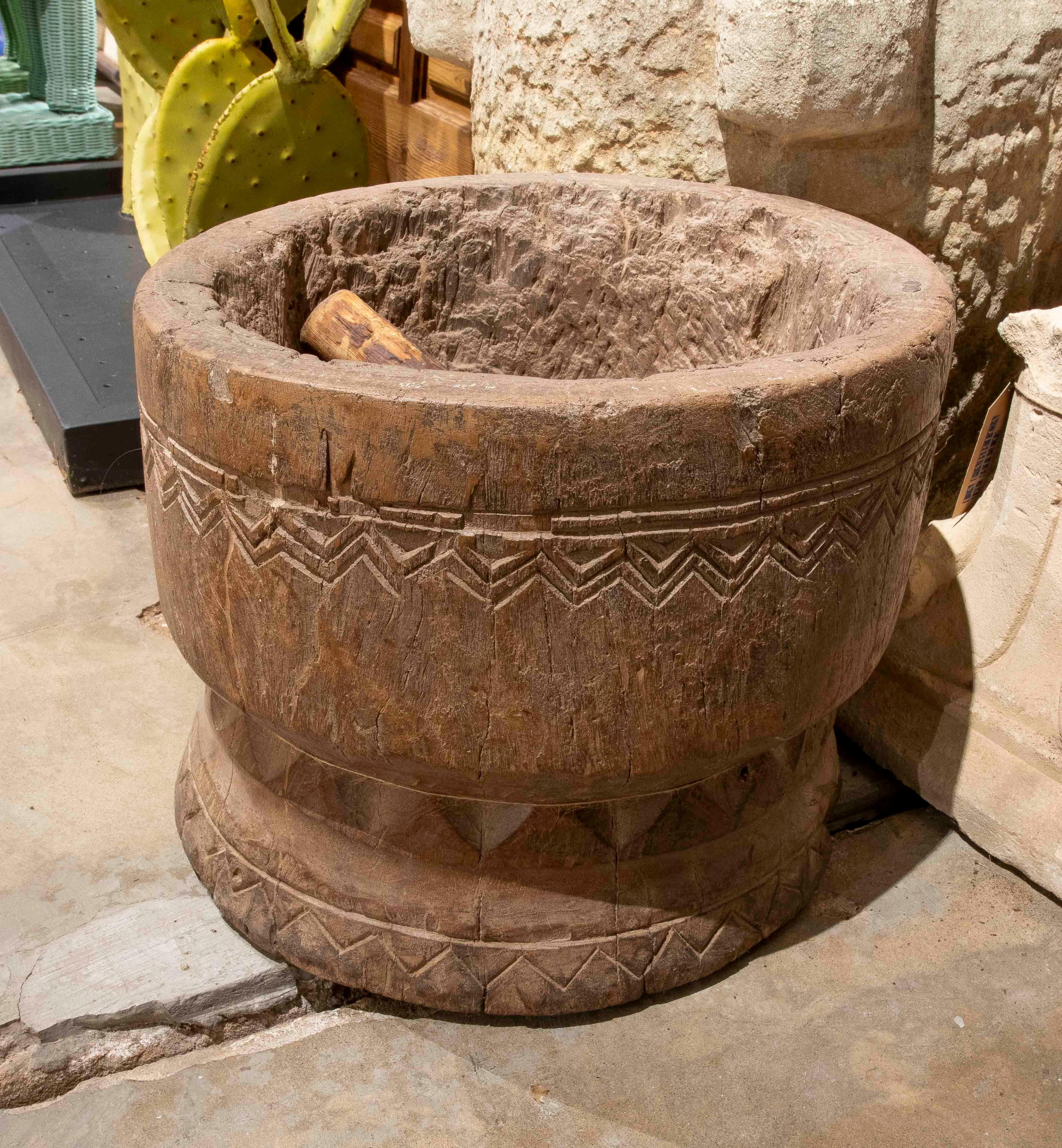 Atemberaubender antiker Mörser, handgeschnitzt aus einem einzigen Block Massivholz, mit geometrisch eingeschnittener Dekoration um den Rand und den Boden. Die raue Textur und die natürliche Patina verraten das Alter und den Gebrauch des Stücks und