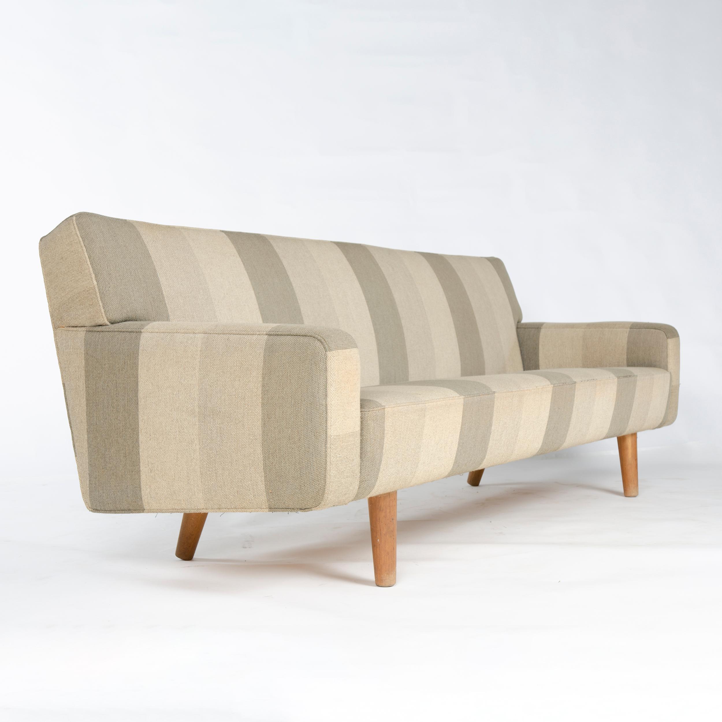 A tailored and fully upholstered sofa floating on well-scaled turned oak dowel legs. Model AP32-S by Hans J. Wegner for A.P. Stolen in original upholstery.