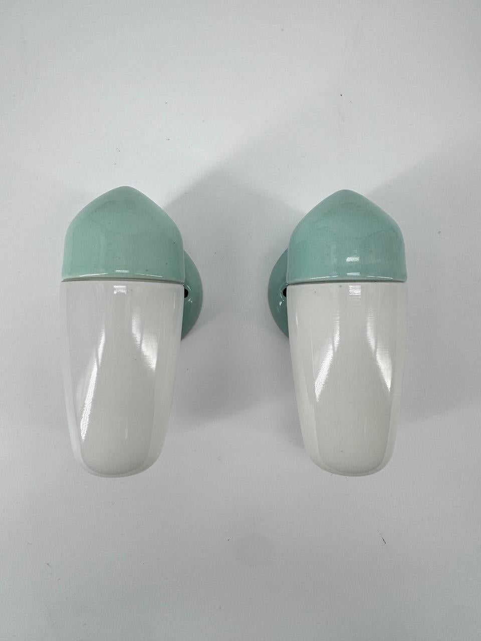 Sconce in a rare aqua blue porcelain and opaline glass shades designed by the German designer Wilhelm Wagenfeld, who studied at the Bauhaus school. 

Dating from 1958 this wall light has sleek, round and elegant lines, a timeless design that will